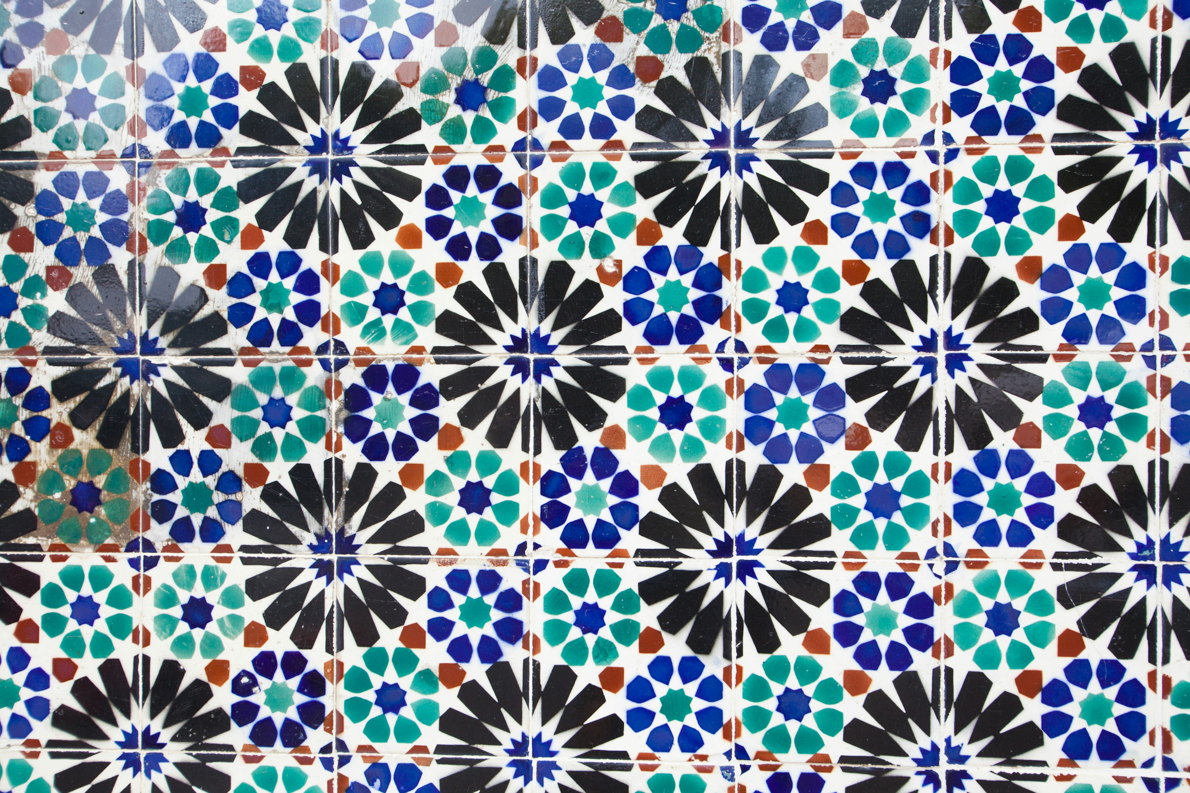 Patrón de azulejos coloridos con flores en azul, verde, negro y rojo