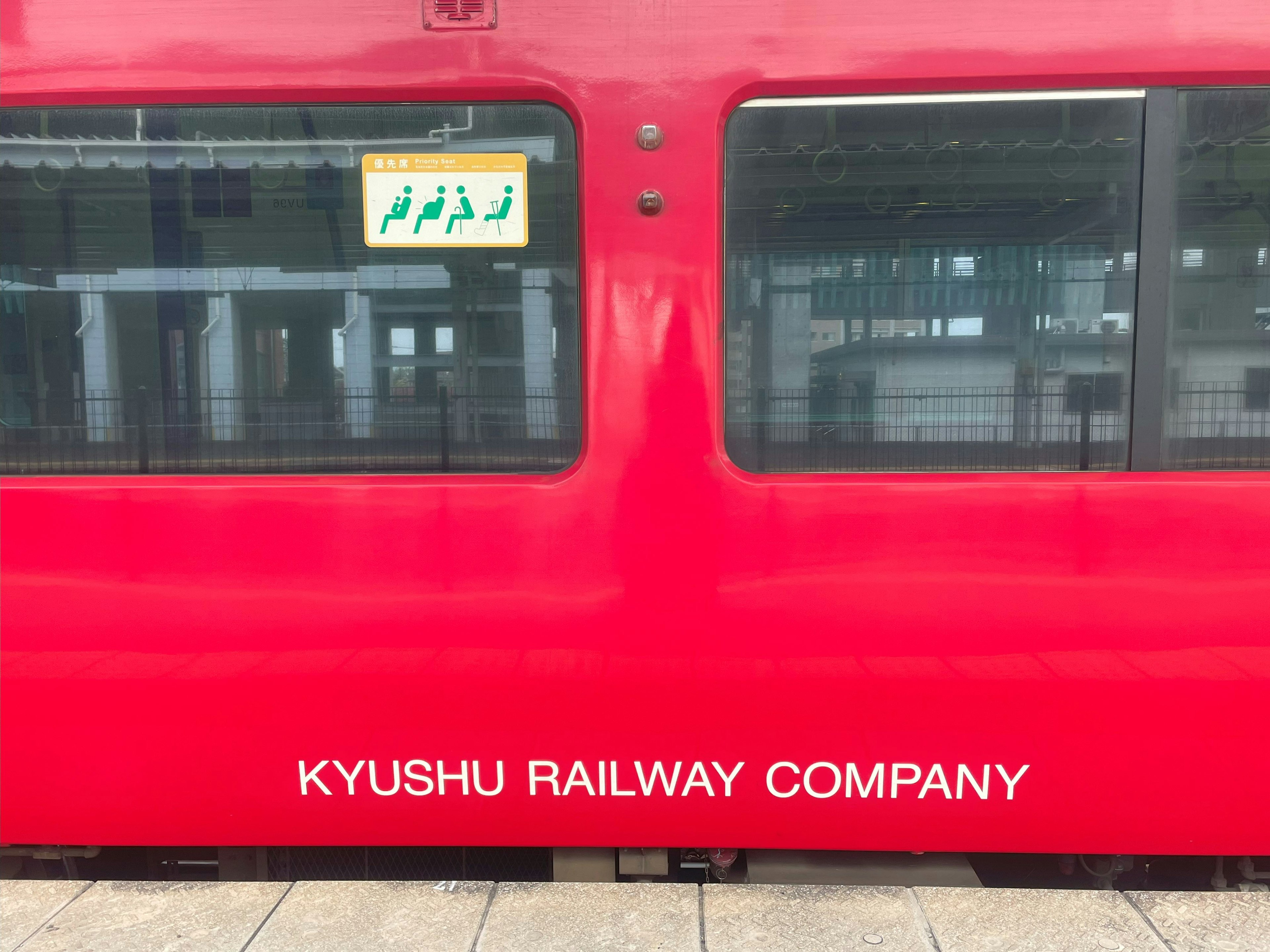 Seitenansicht eines roten Zuges mit dem Logo der Kyushu Railway Company und Fenstern