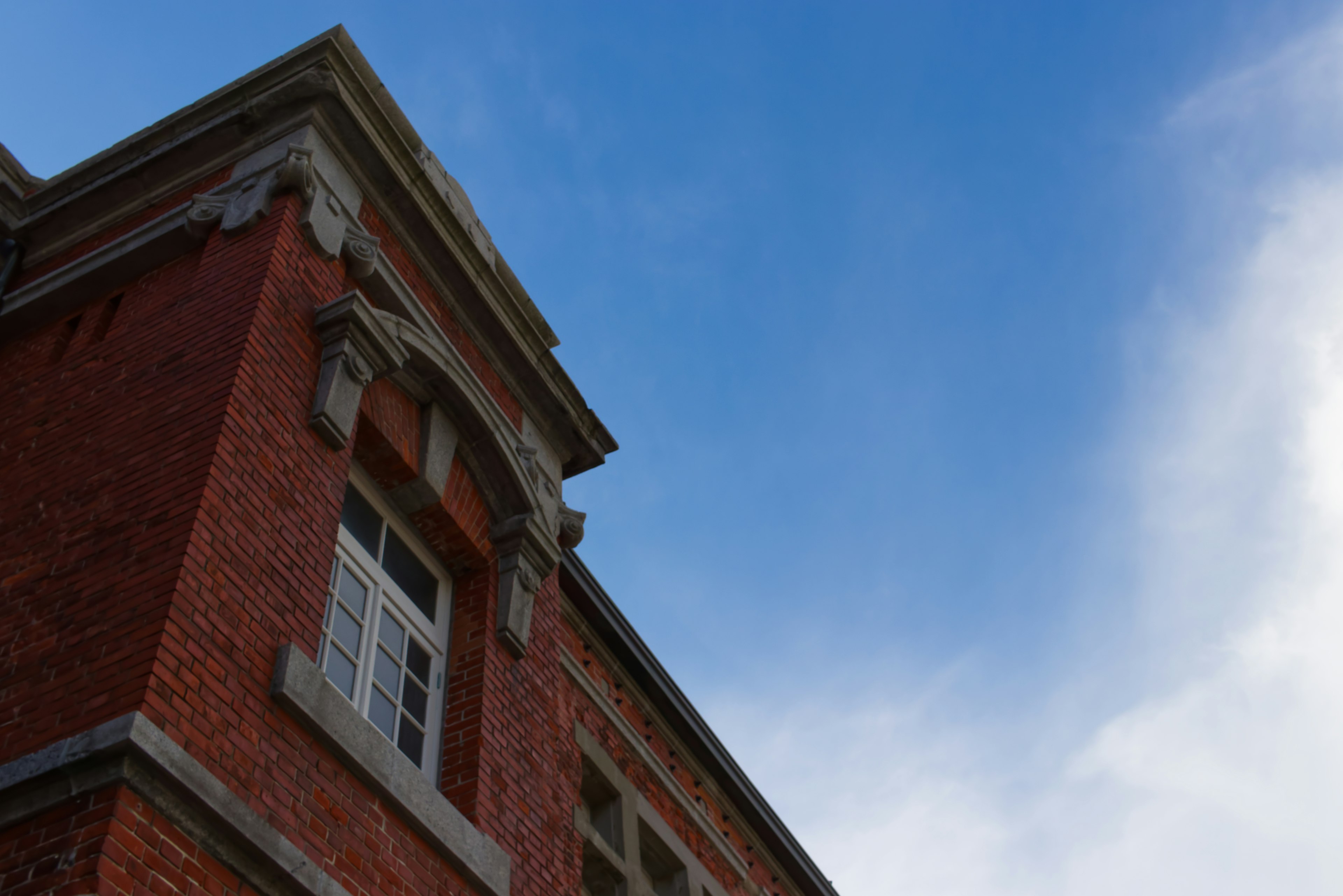 Ecke eines roten Backsteingebäudes vor blauem Himmel