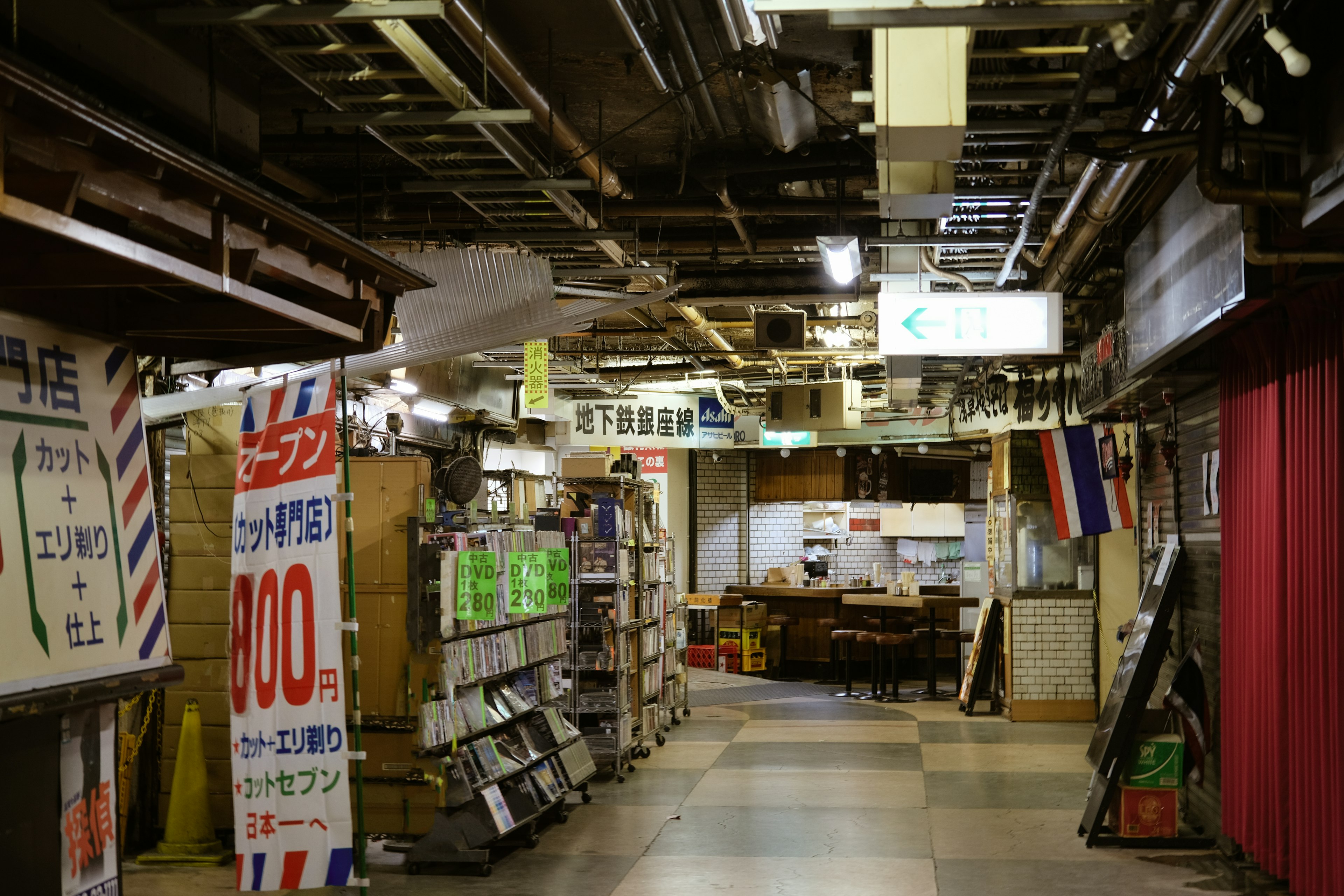 Couloir étroit avec des enseignes de magasins et des produits visibles dans une zone commerciale