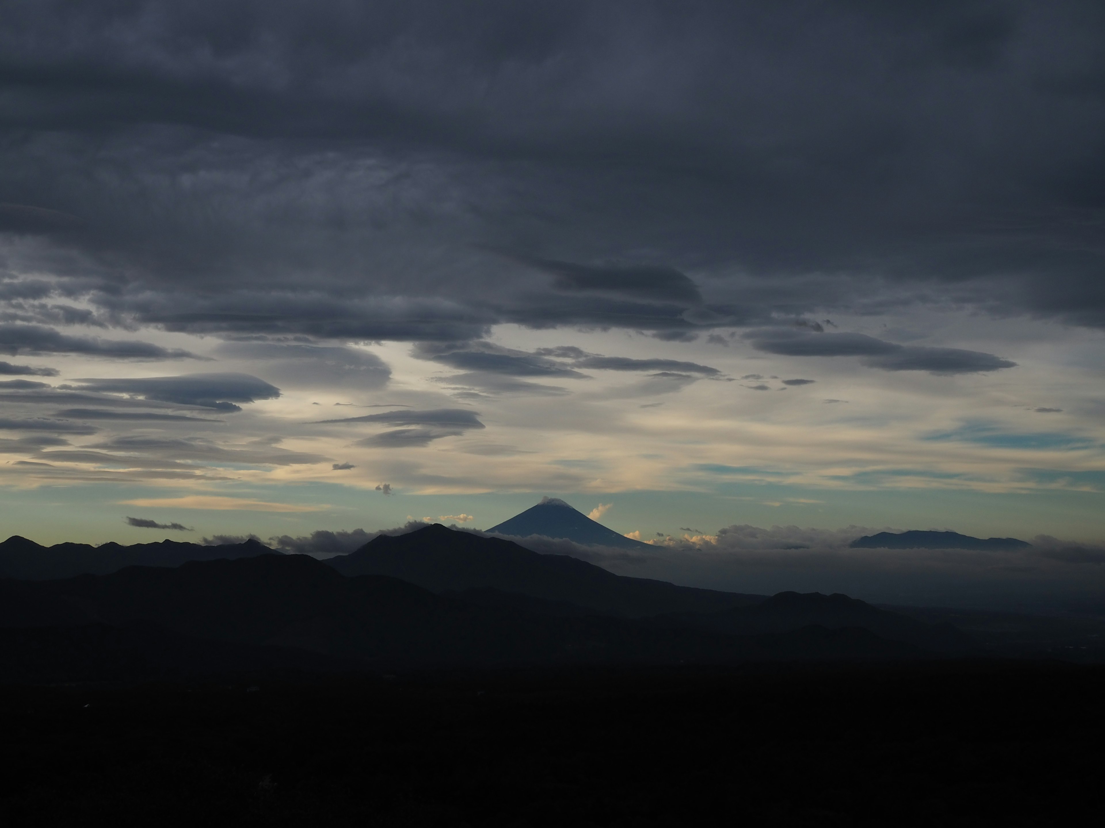 Paysage montagneux dramatique sous des nuages sombres avec un sommet lointain