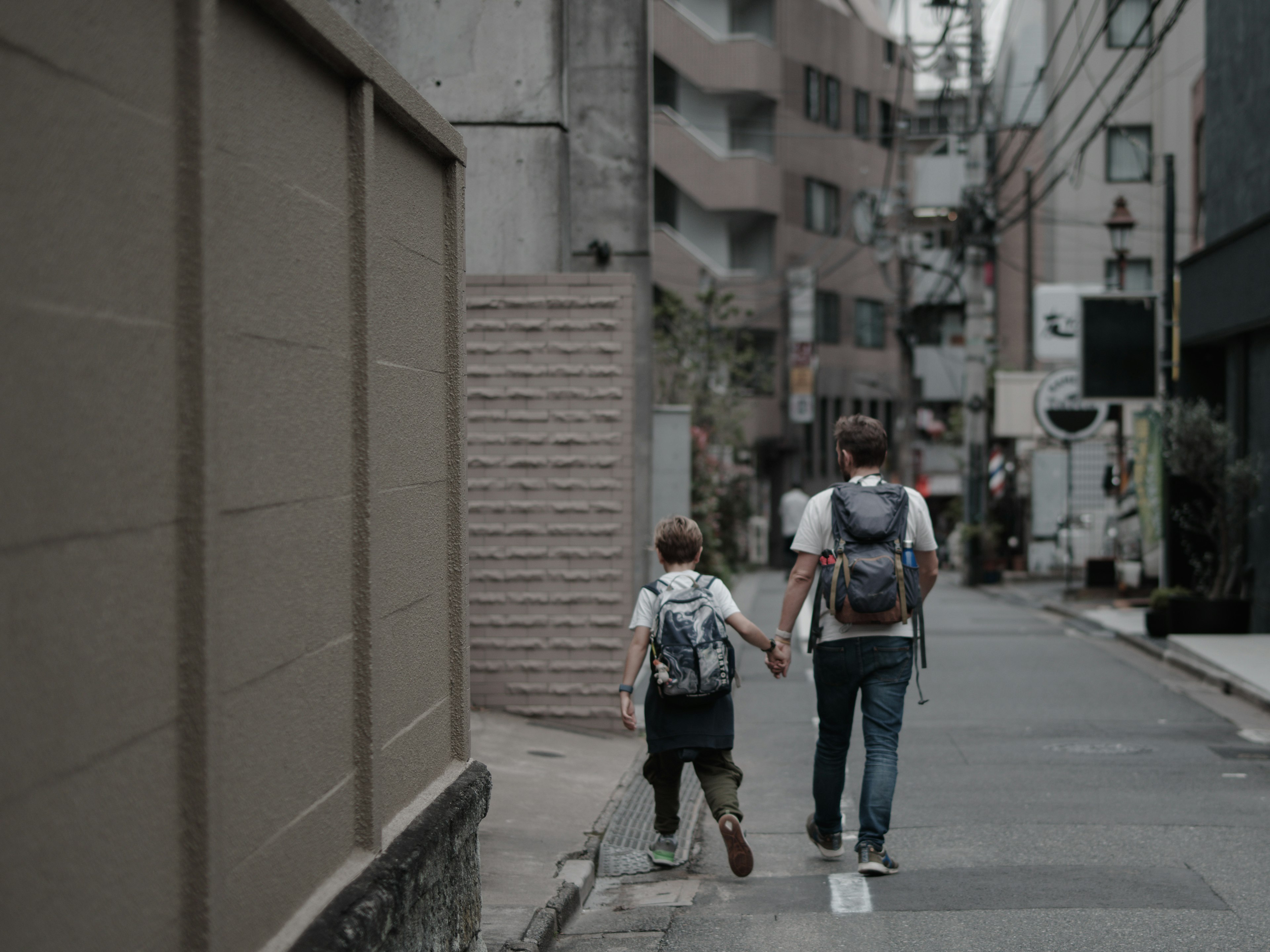 Un padre y un hijo caminando de la mano por una calle de la ciudad