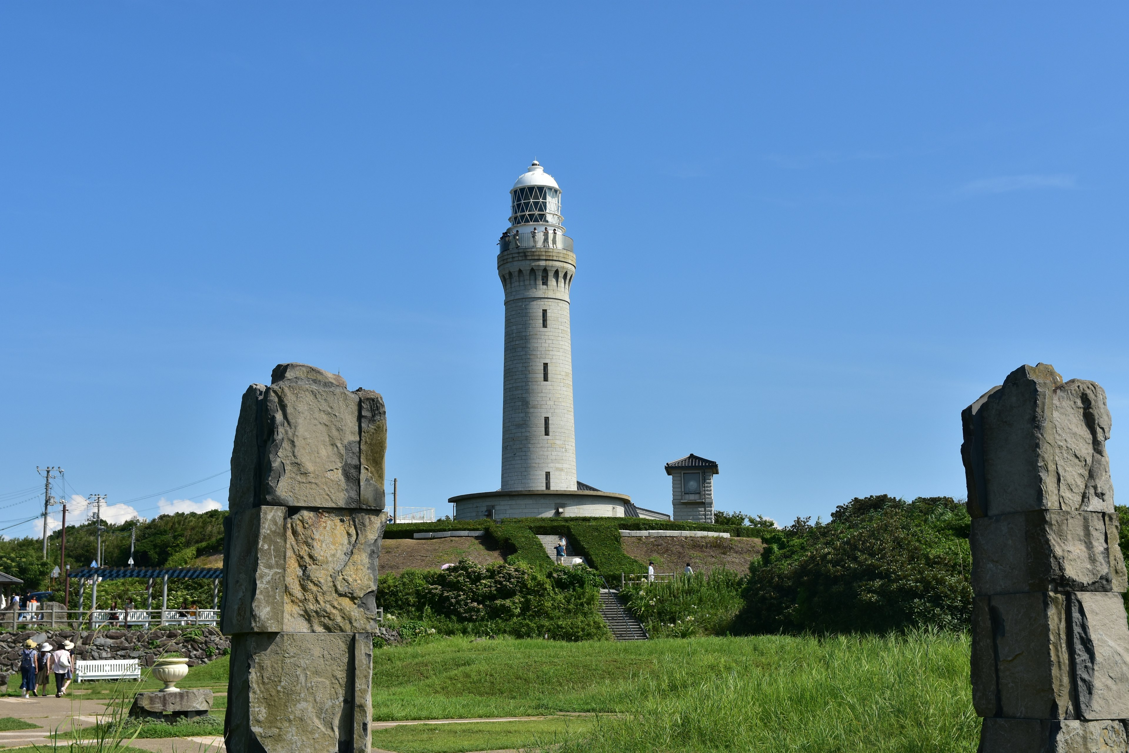 Lighthouse standing under a blue sky surrounded by green grass