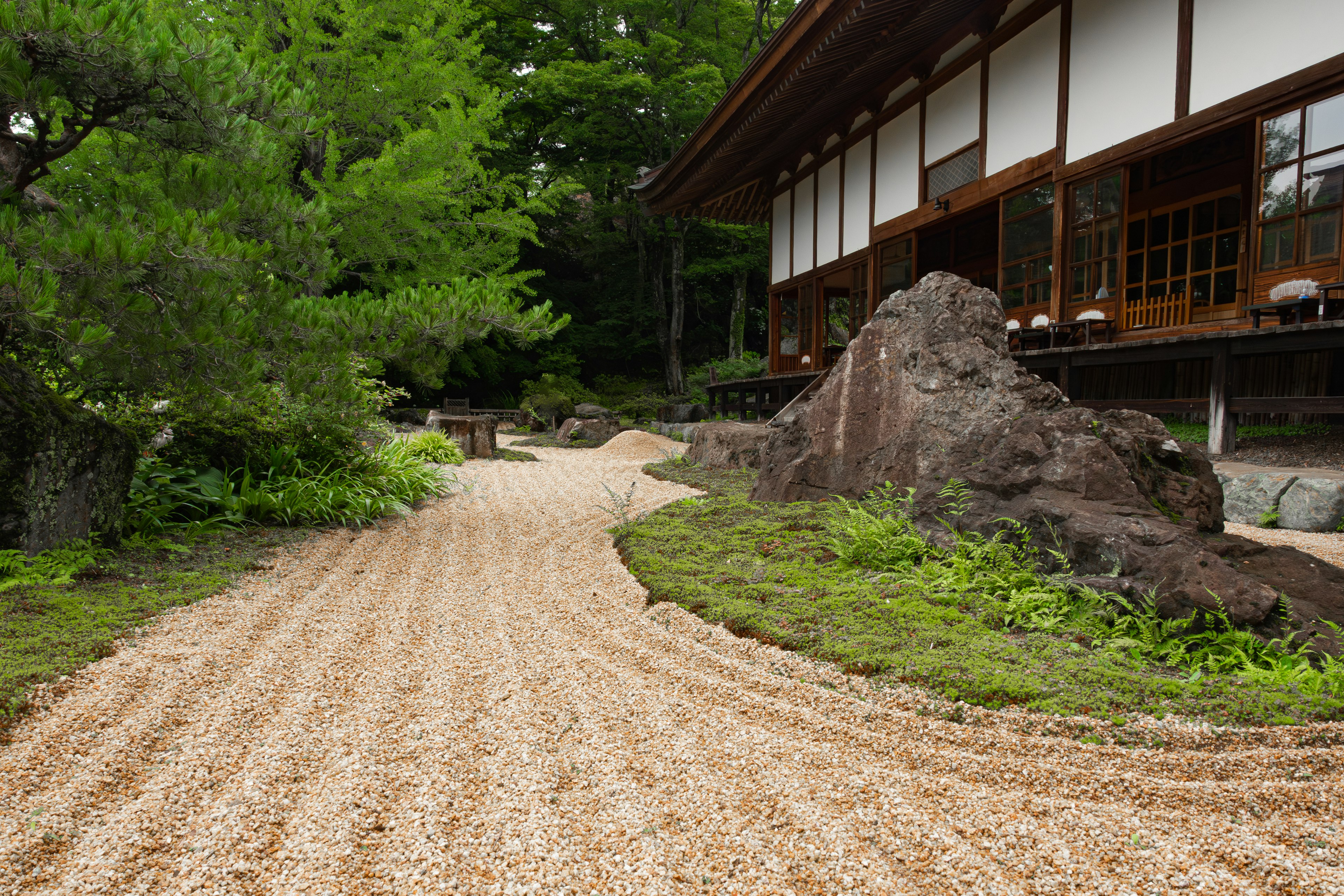 Traditionelles japanisches Gebäude mit einem Kiesweg und Steinen in einem Garten