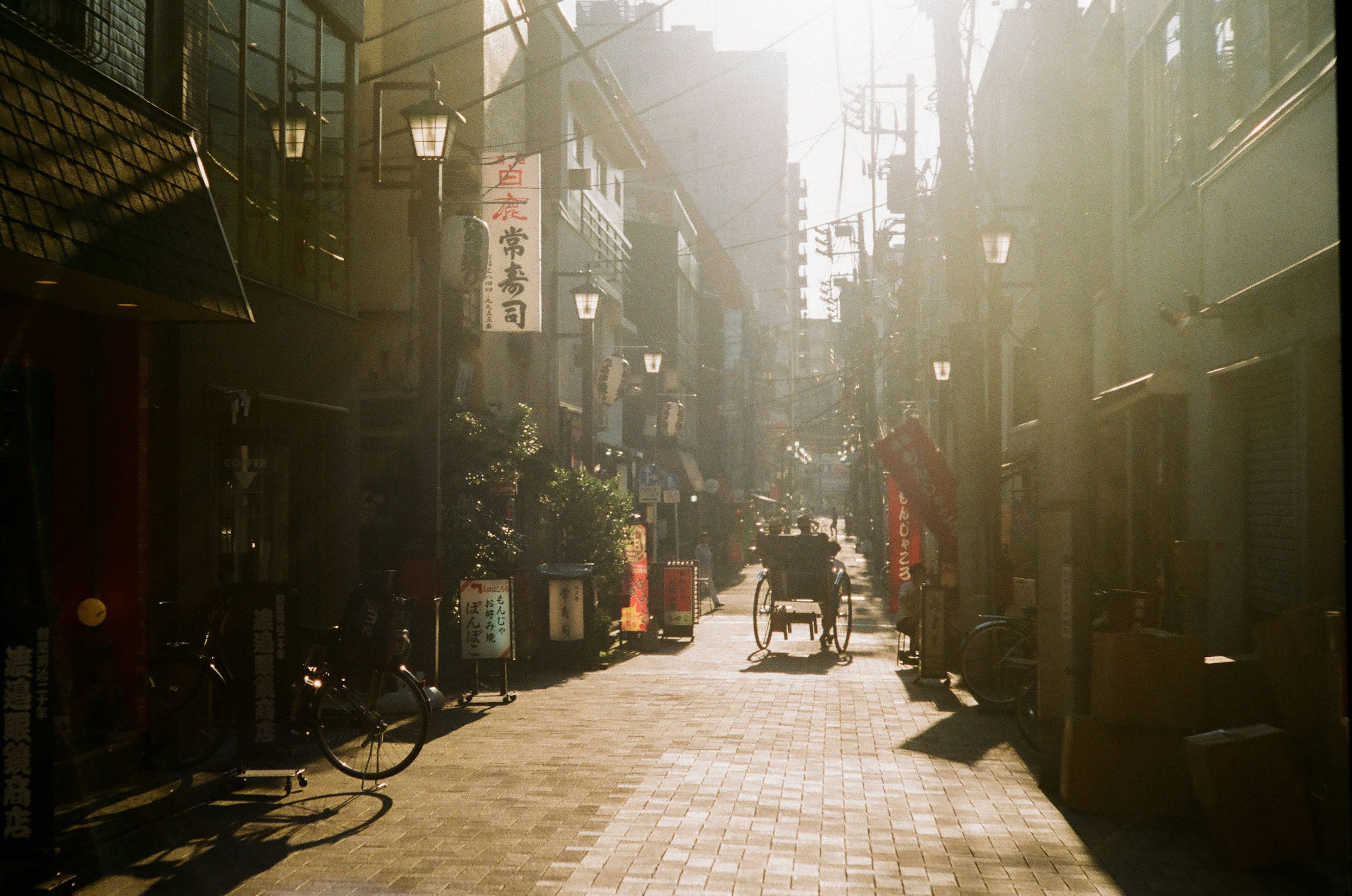 Narrow alleyway with sunlight filtering through featuring bicycles and shop signs