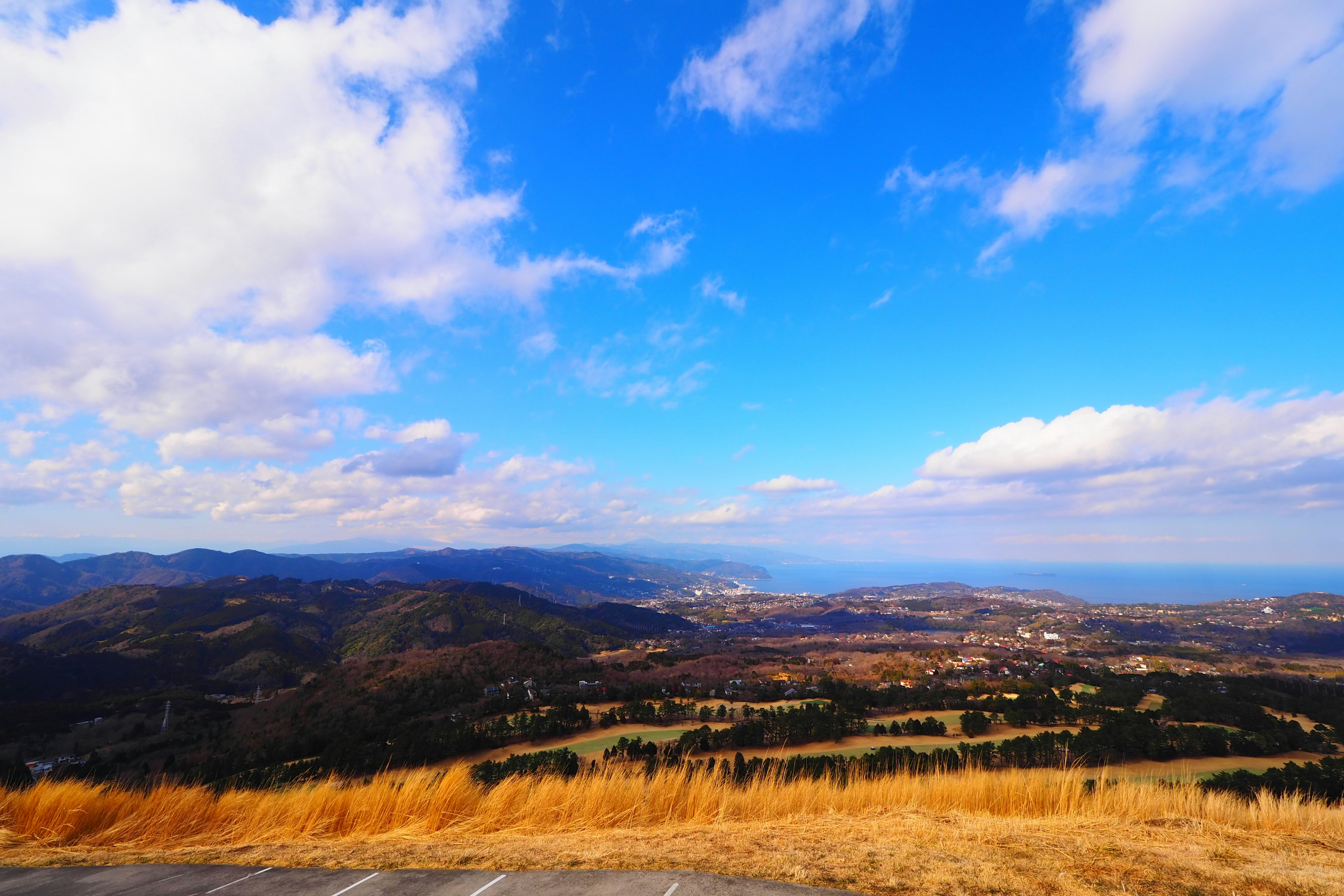 Vasto cielo blu con nuvole su colline verdi e vista sul mare