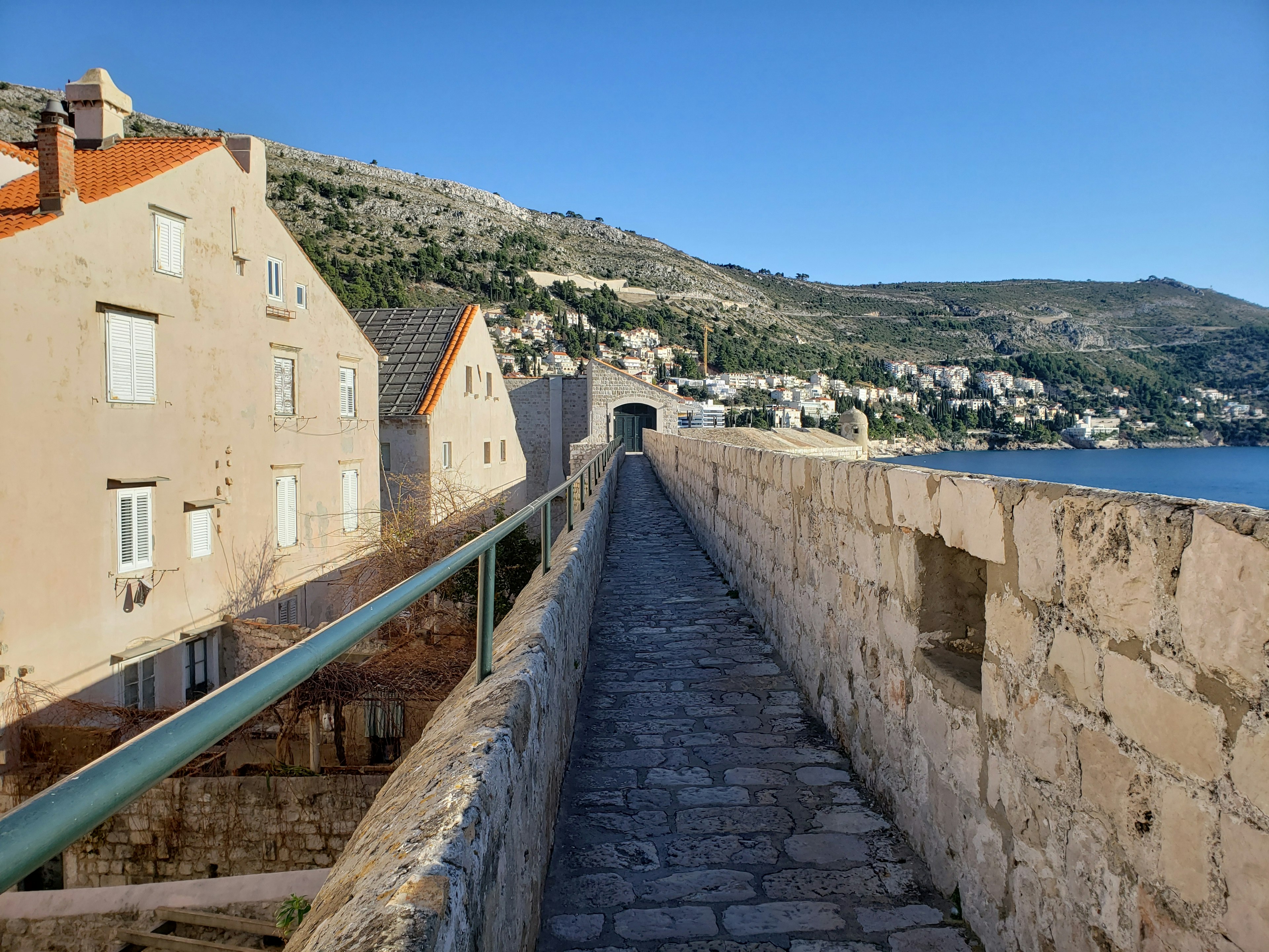 Sentiero in pietra lungo un muro di fortezza con vista sul mare