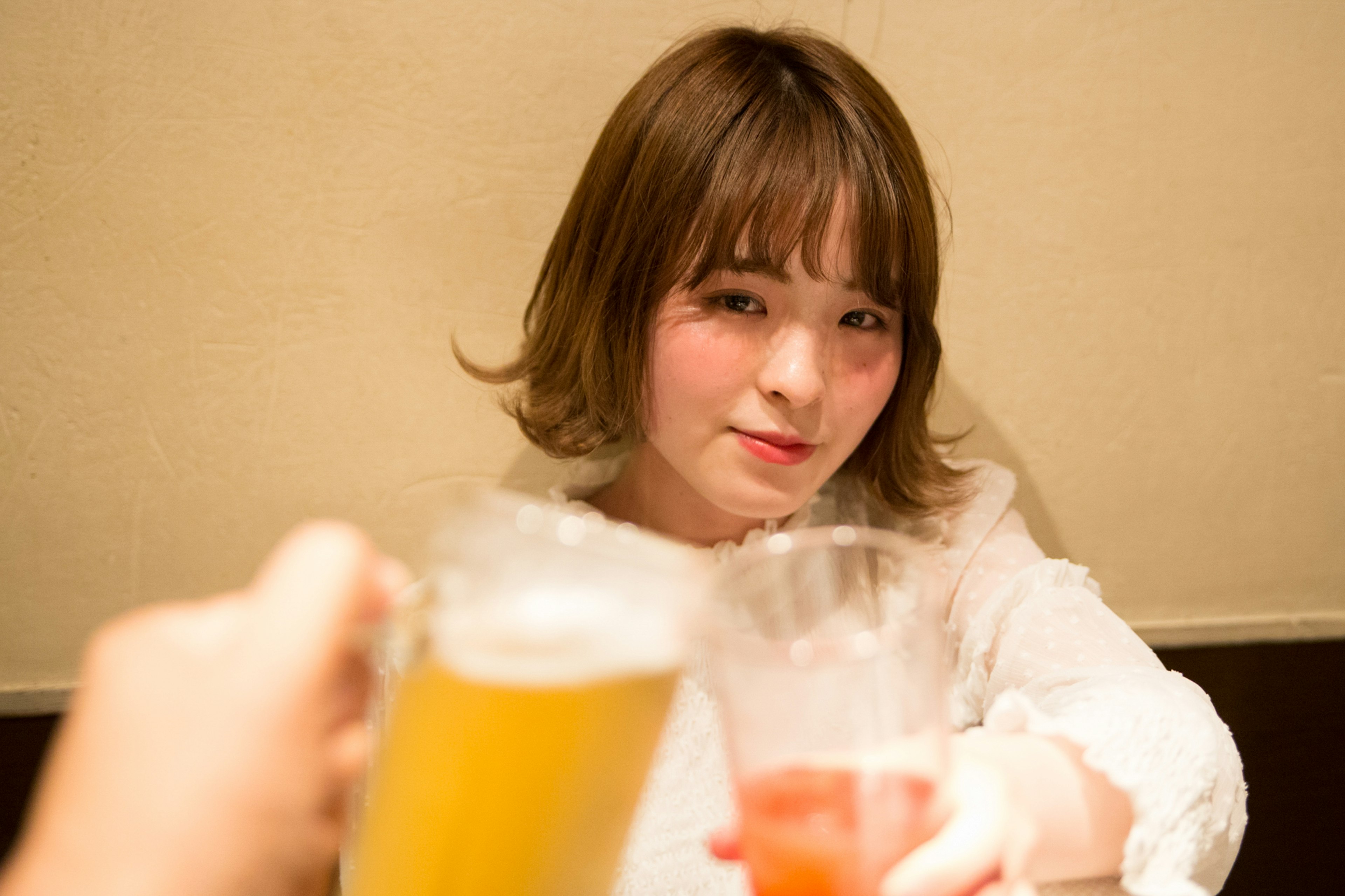 A woman smiling while holding a cocktail and beer