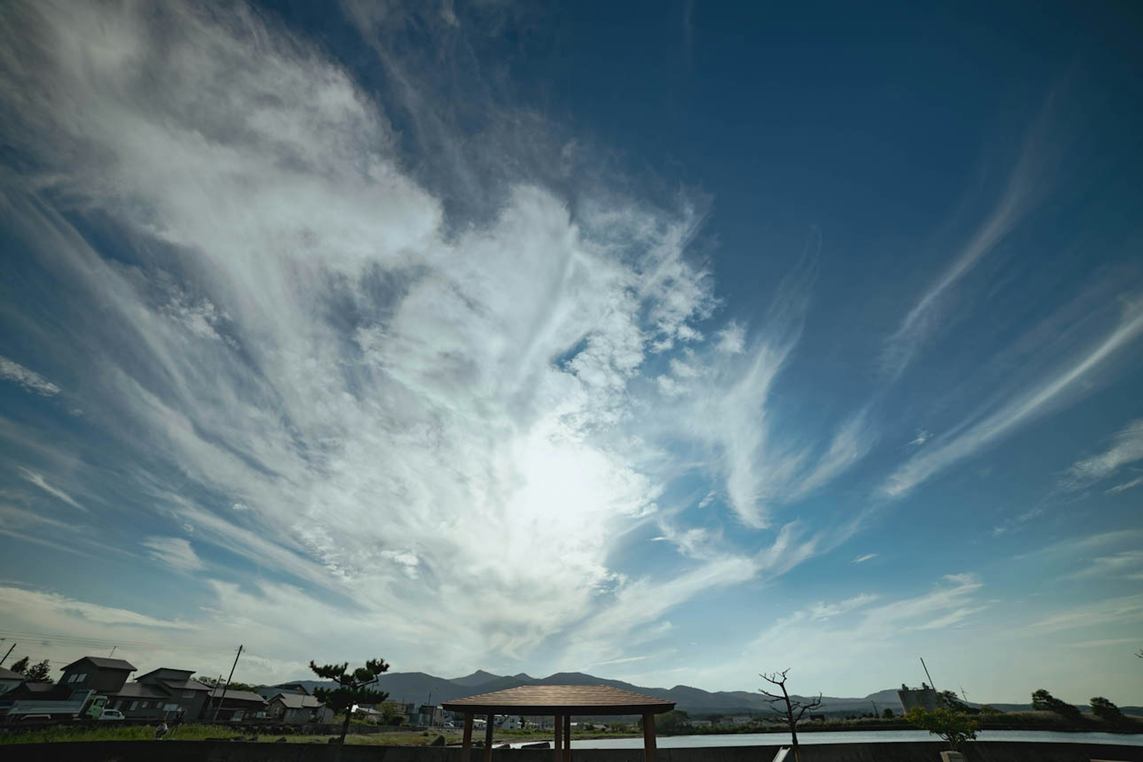 Una vista panoramica di un lago sotto un cielo blu con nuvole sottili