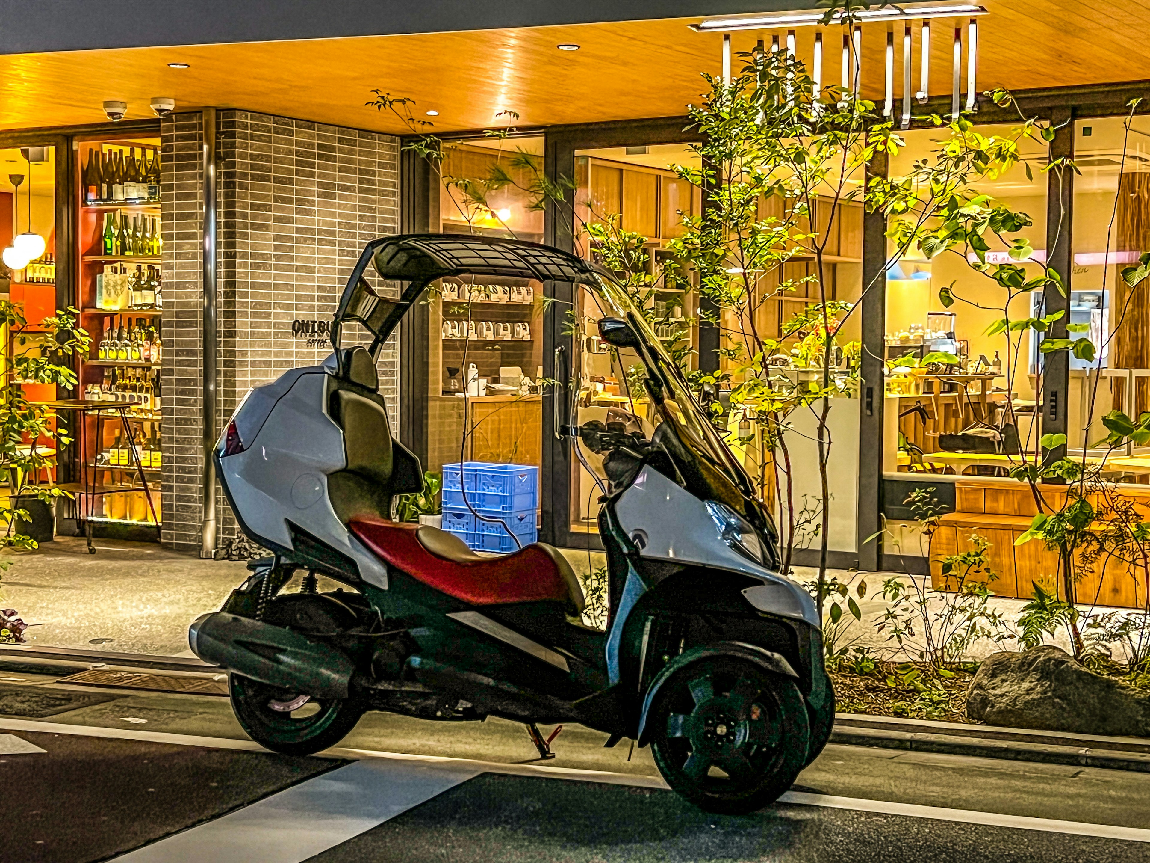 Three-wheeled scooter parked in front of a cafe at night