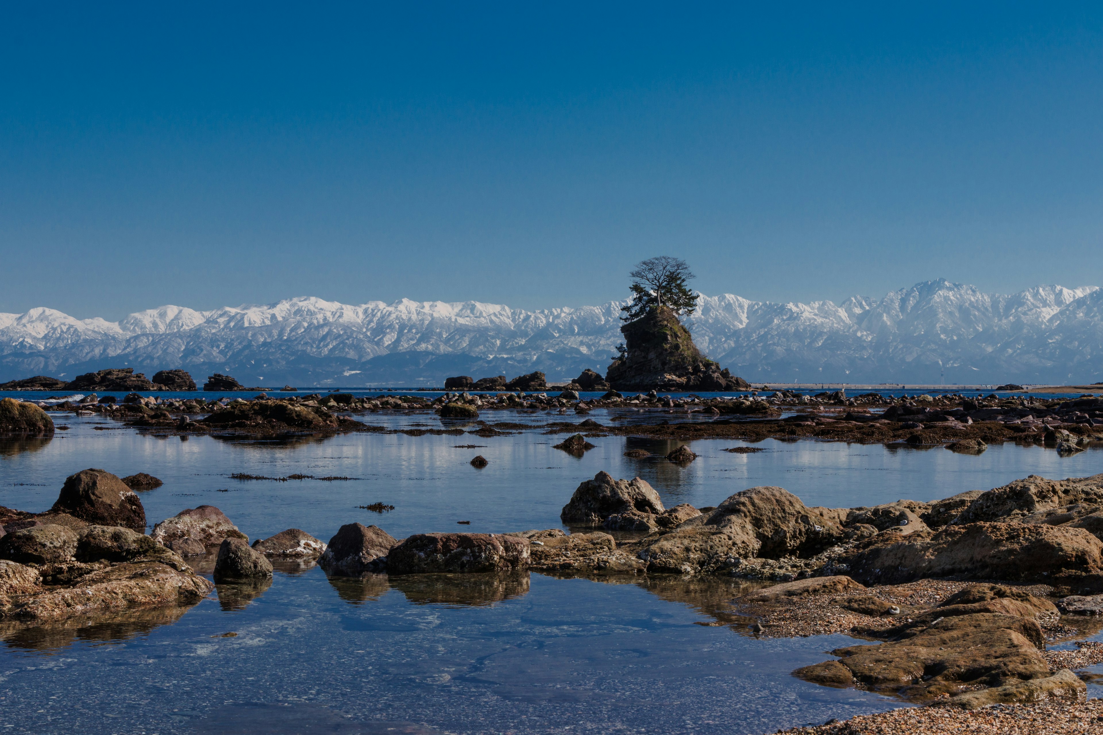 海岸风景岩石和潮池背景有雪山