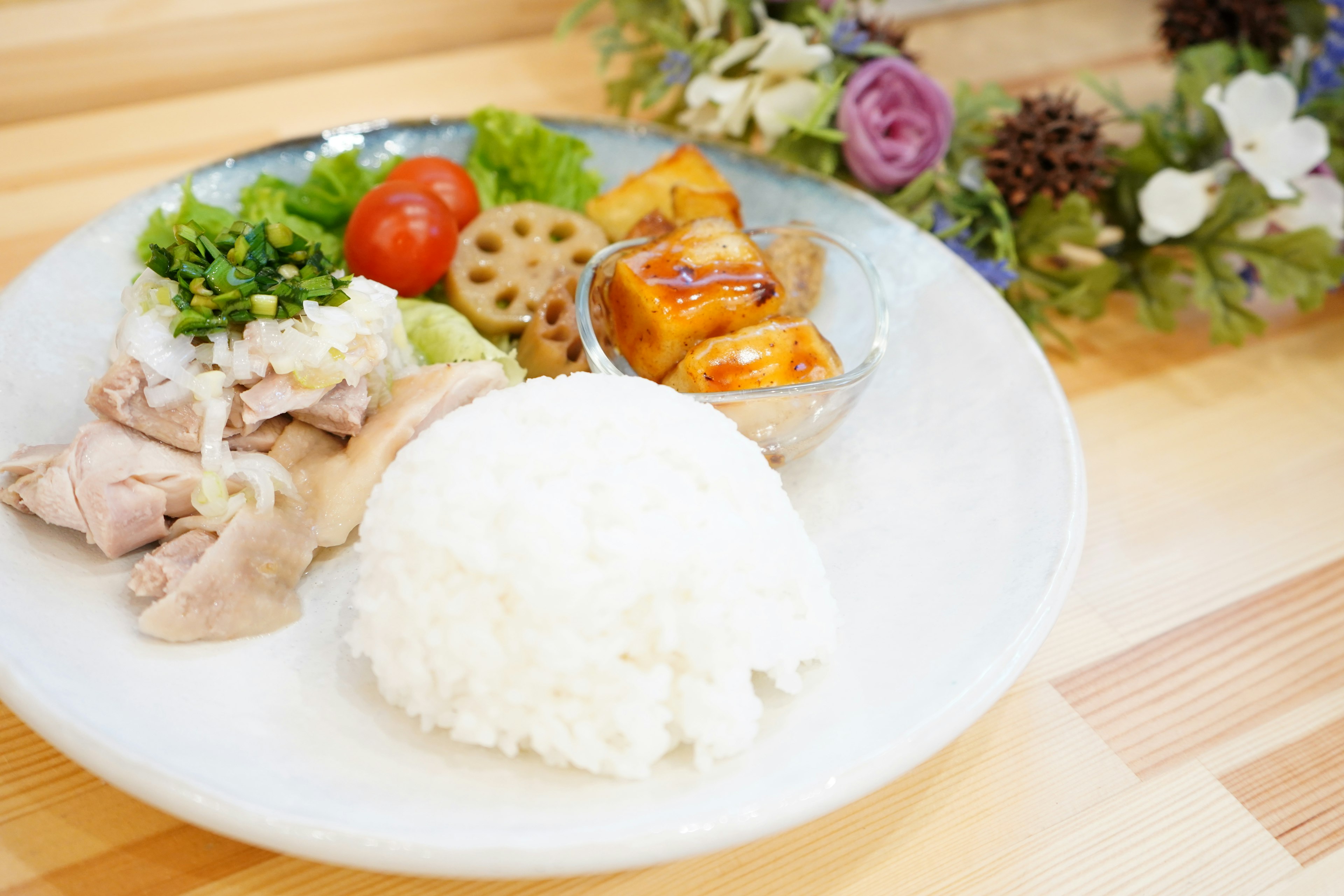 盤子上有蒸米飯、雞肉和新鮮蔬菜以及配菜