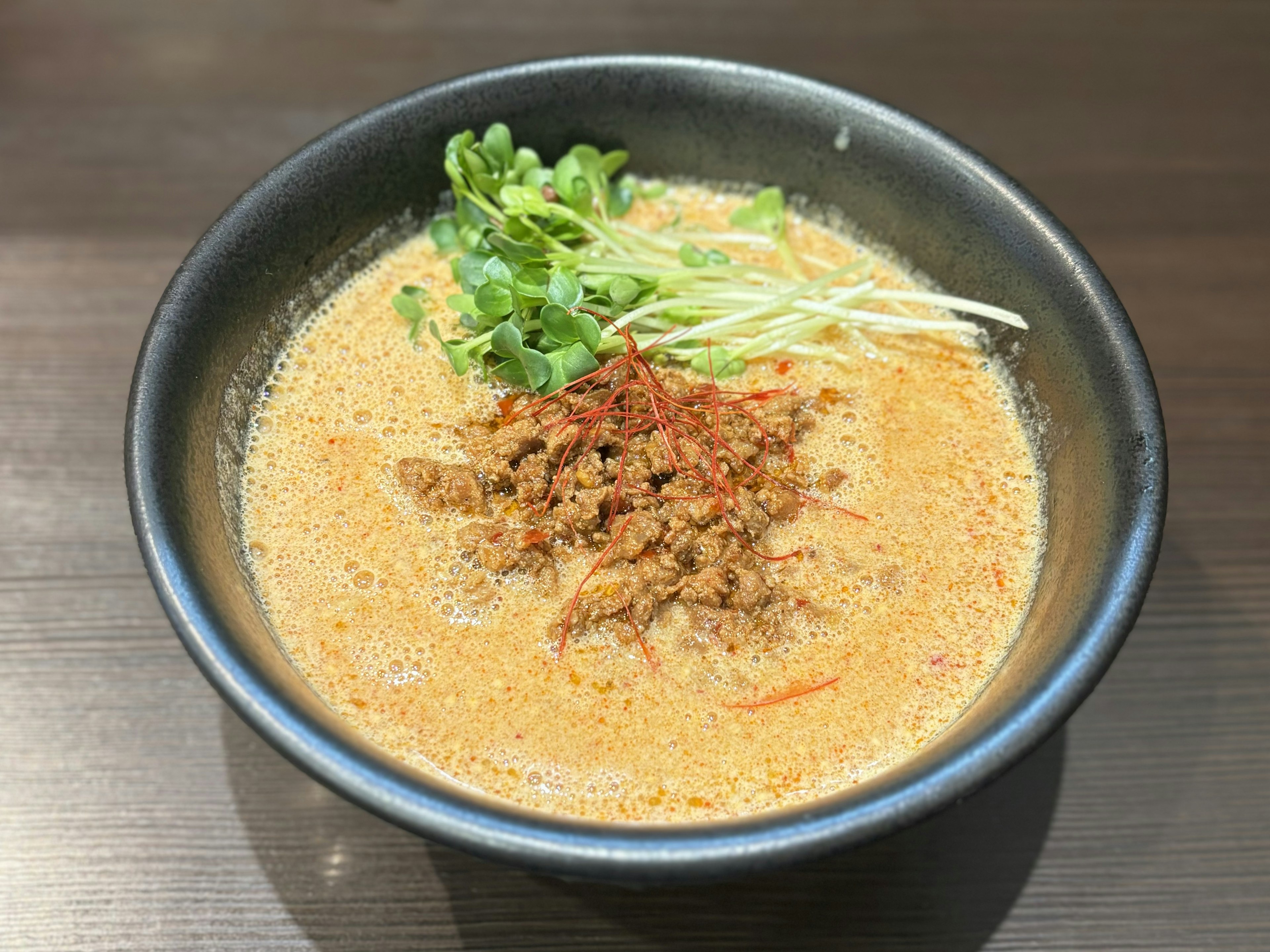 クリーミーなスープに肉のトッピングと青菜が乗ったラーメン