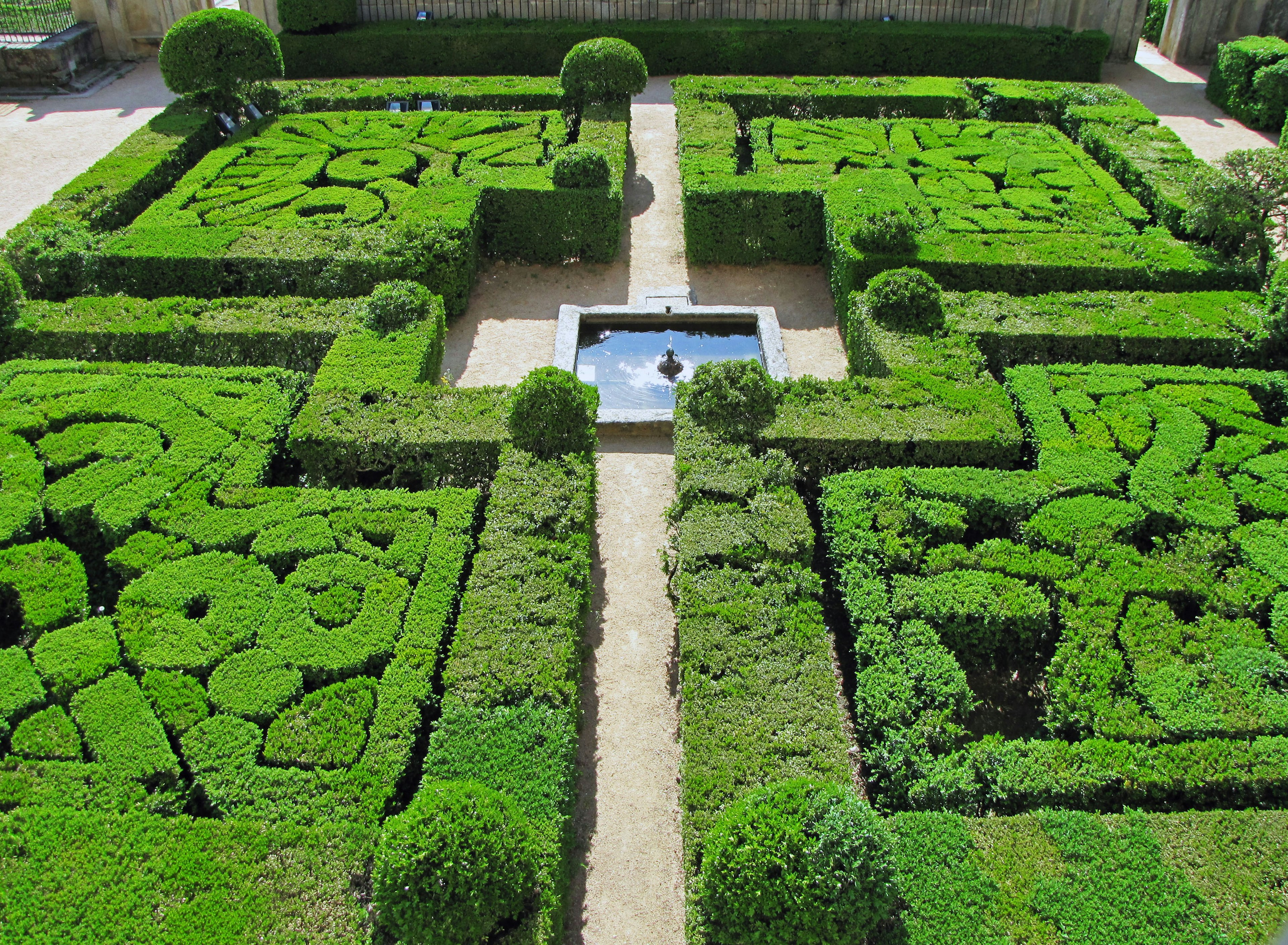 Vista aerea di un giardino geometrico lussureggiante con siepi ben curate e una fontana centrale