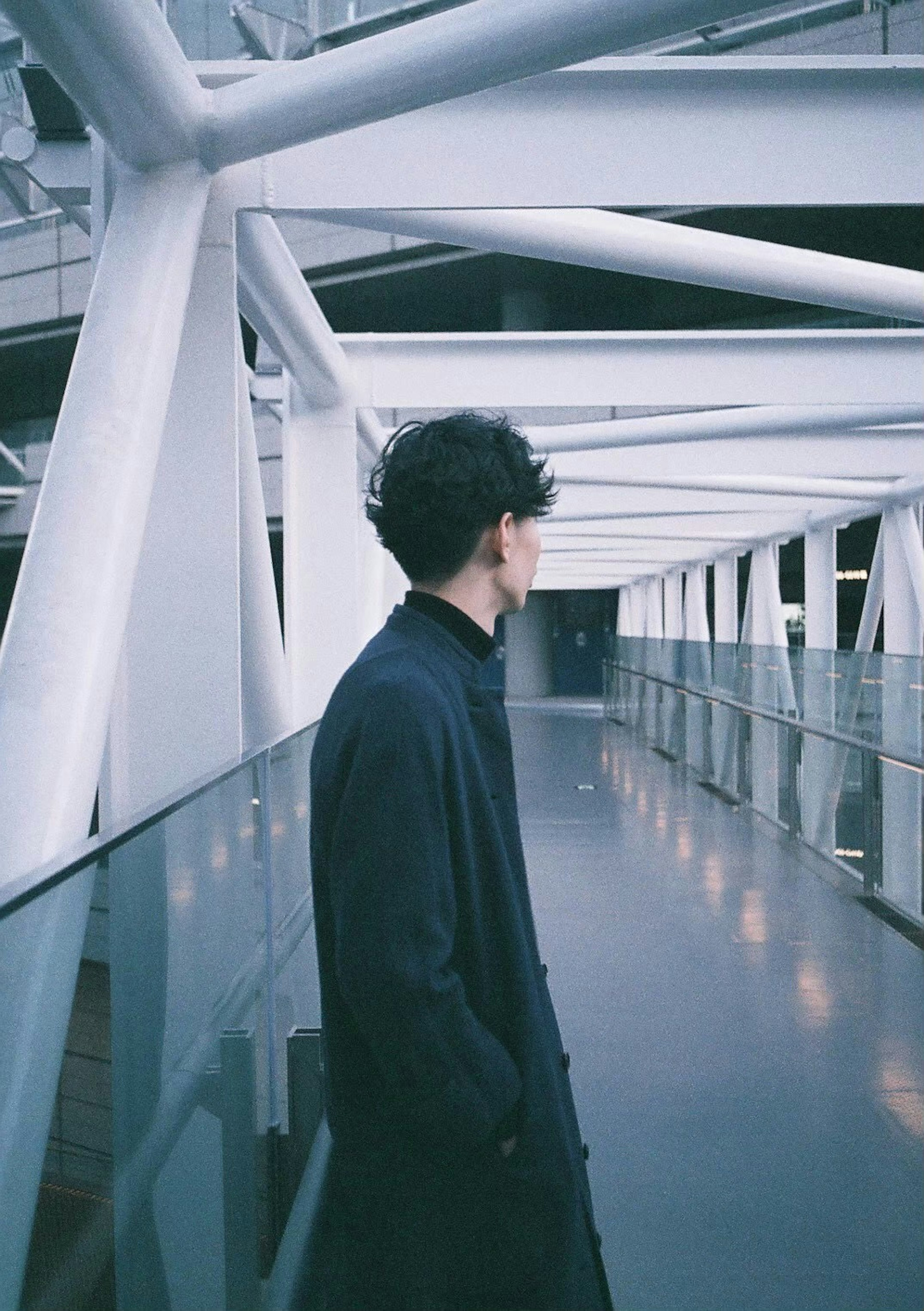 A person standing in a modern corridor under white structural beams