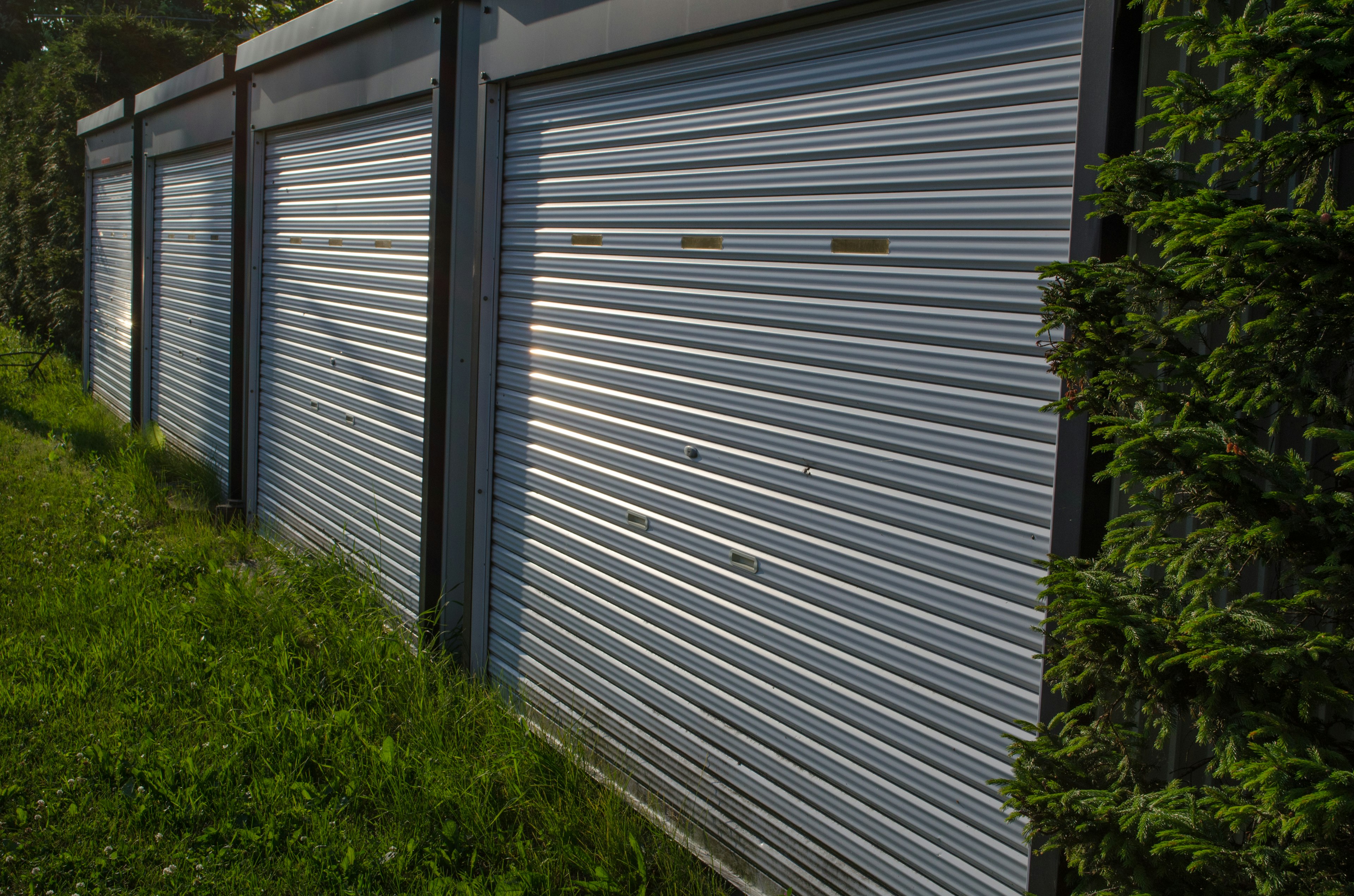 Fila di serrande per garage argentate con erba verde in primo piano