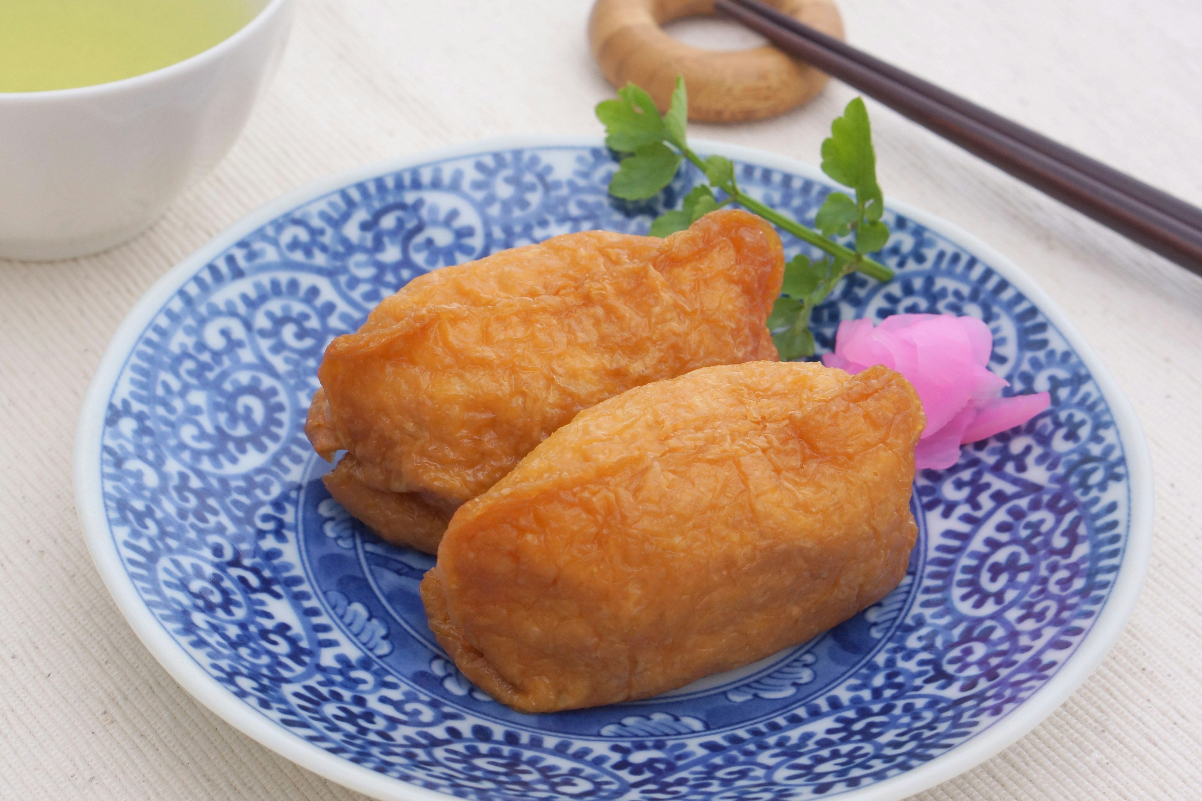 Two fried rice balls on a beautiful blue plate with pink pickled ginger