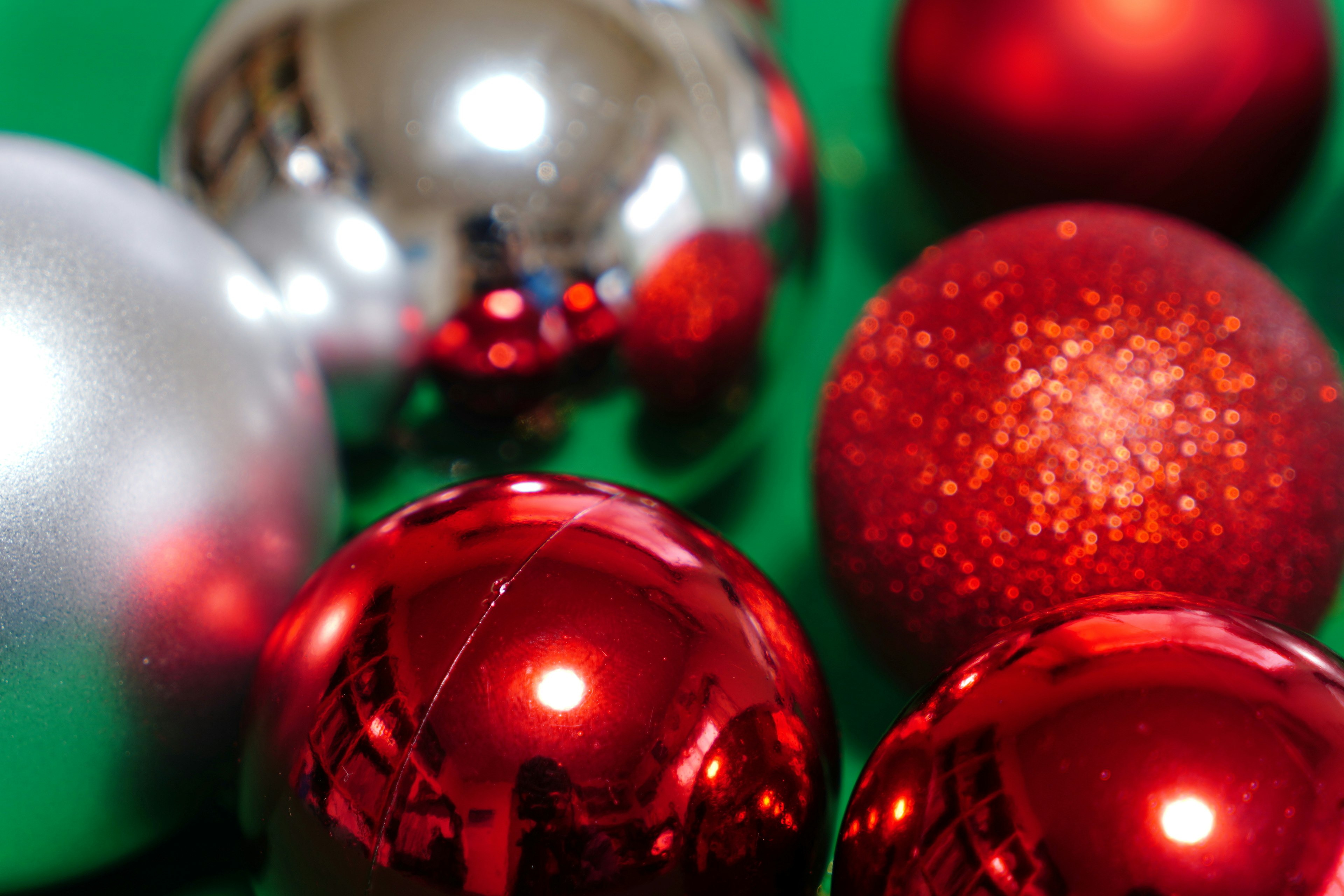 Red and silver Christmas ornaments arranged on a green background