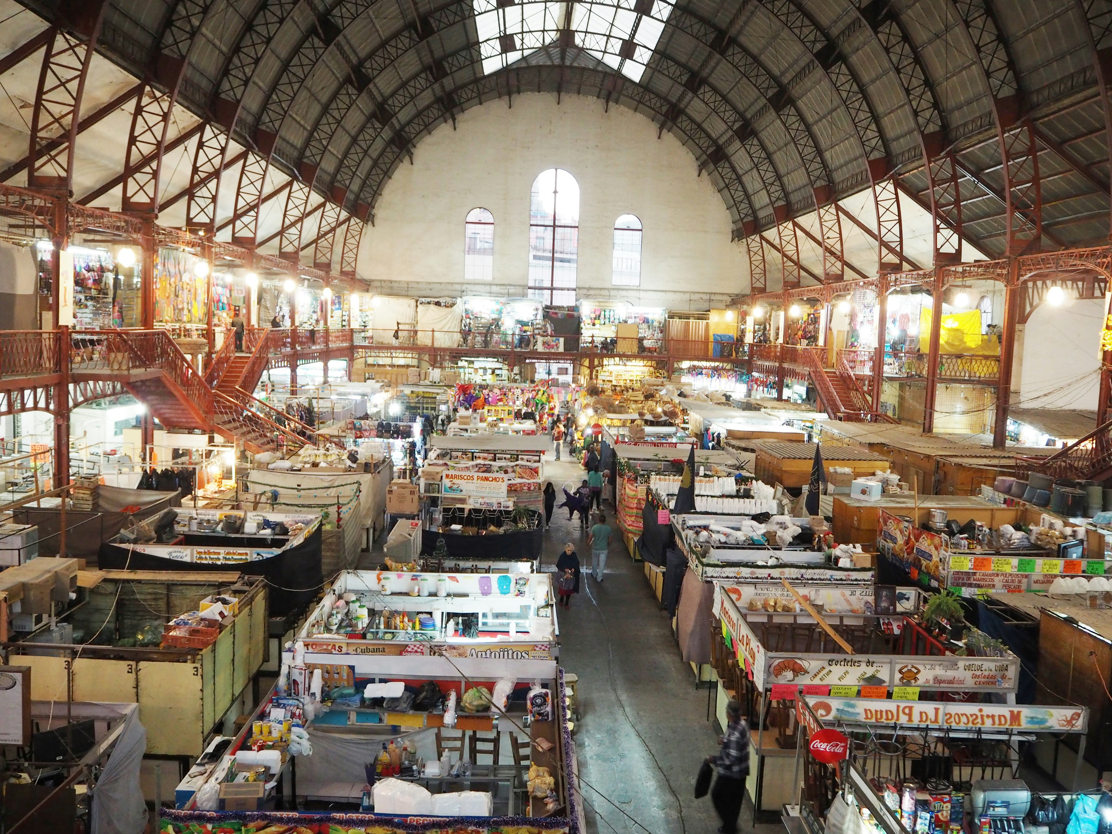 Panoramic view of a spacious market interior featuring numerous stalls in a vibrant atmosphere