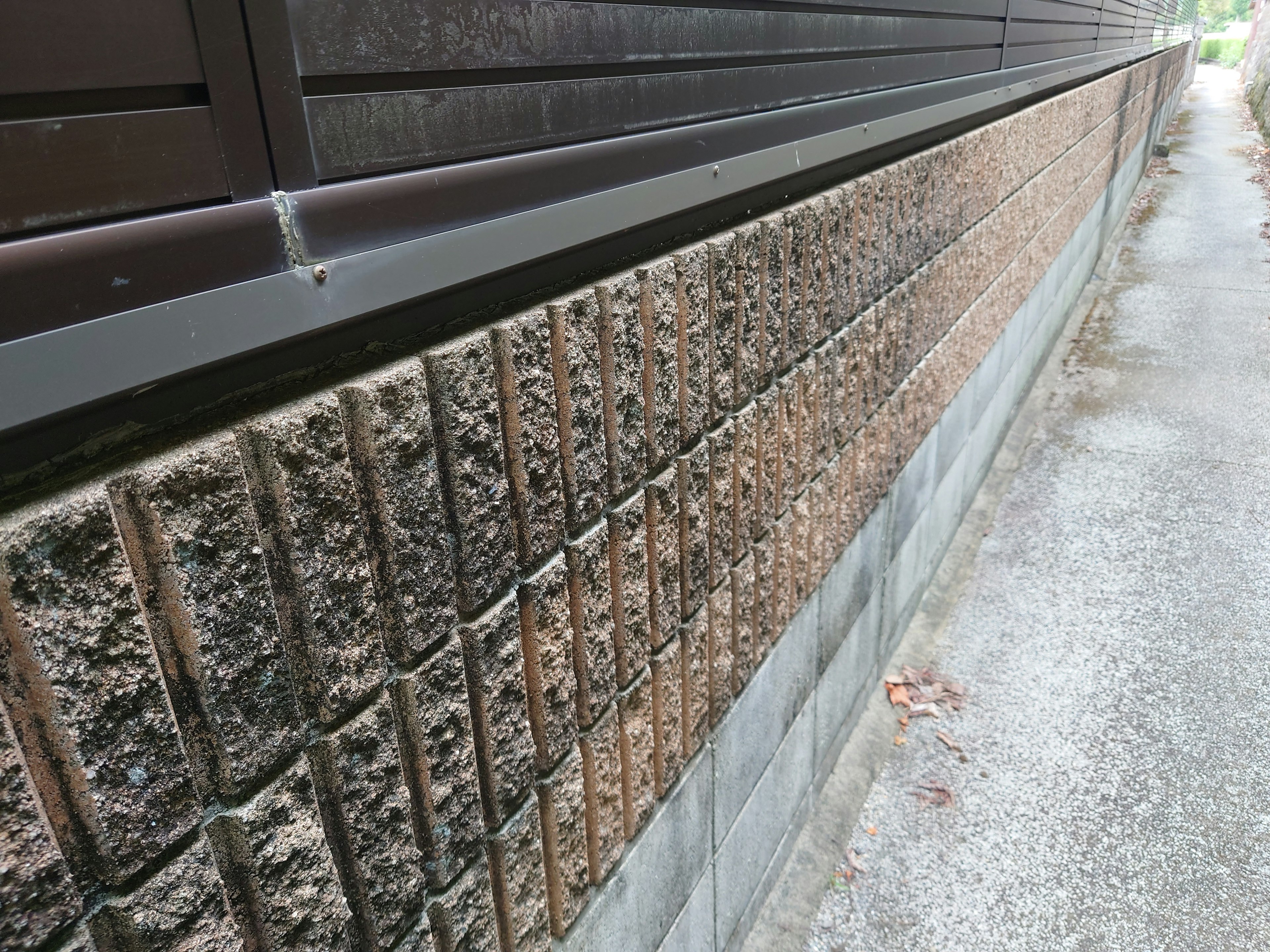 Primo piano di un muro in cemento con un marciapiede pavimentato