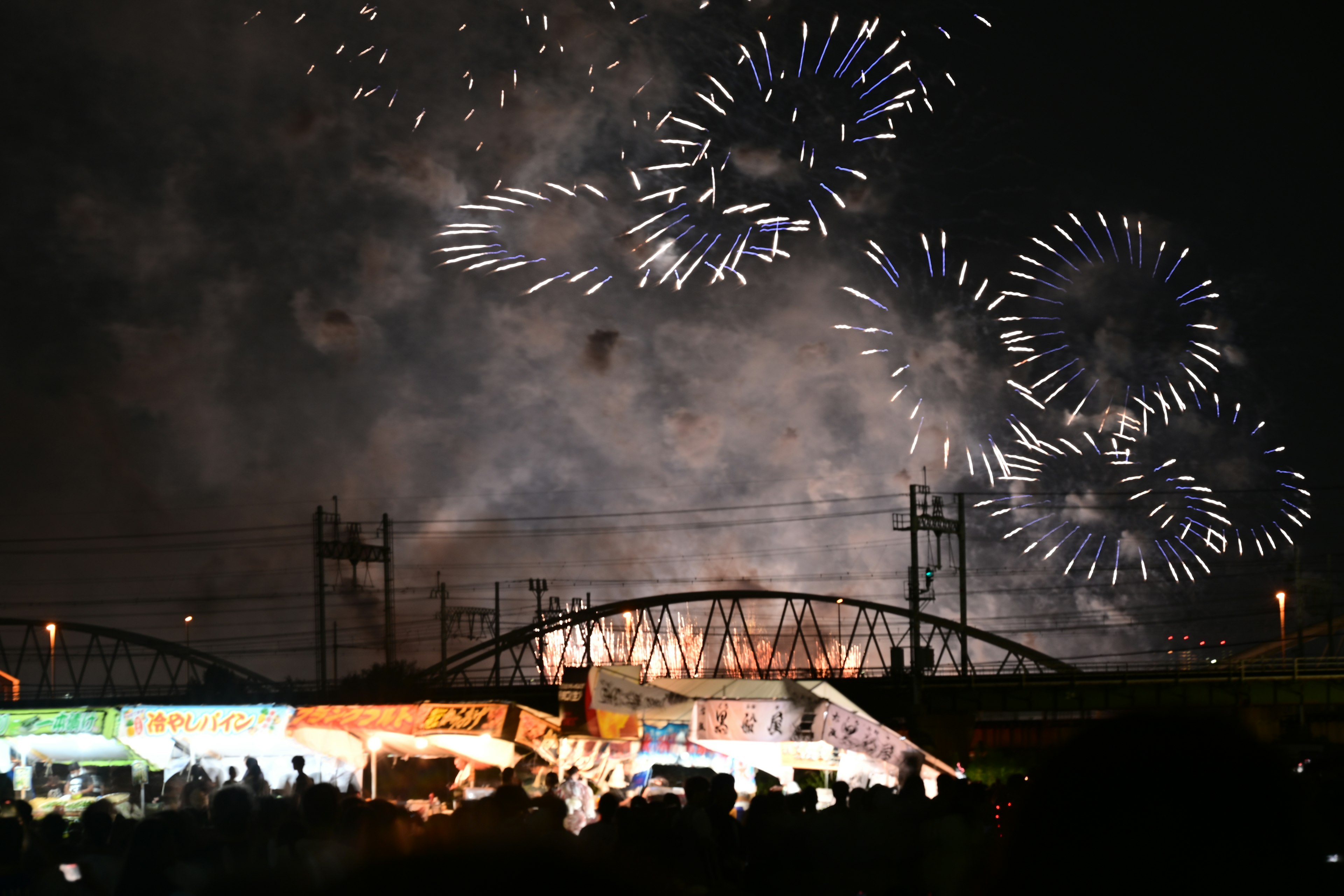 Fuochi d'artificio che illuminano il cielo notturno con bancarelle vivaci sottostanti