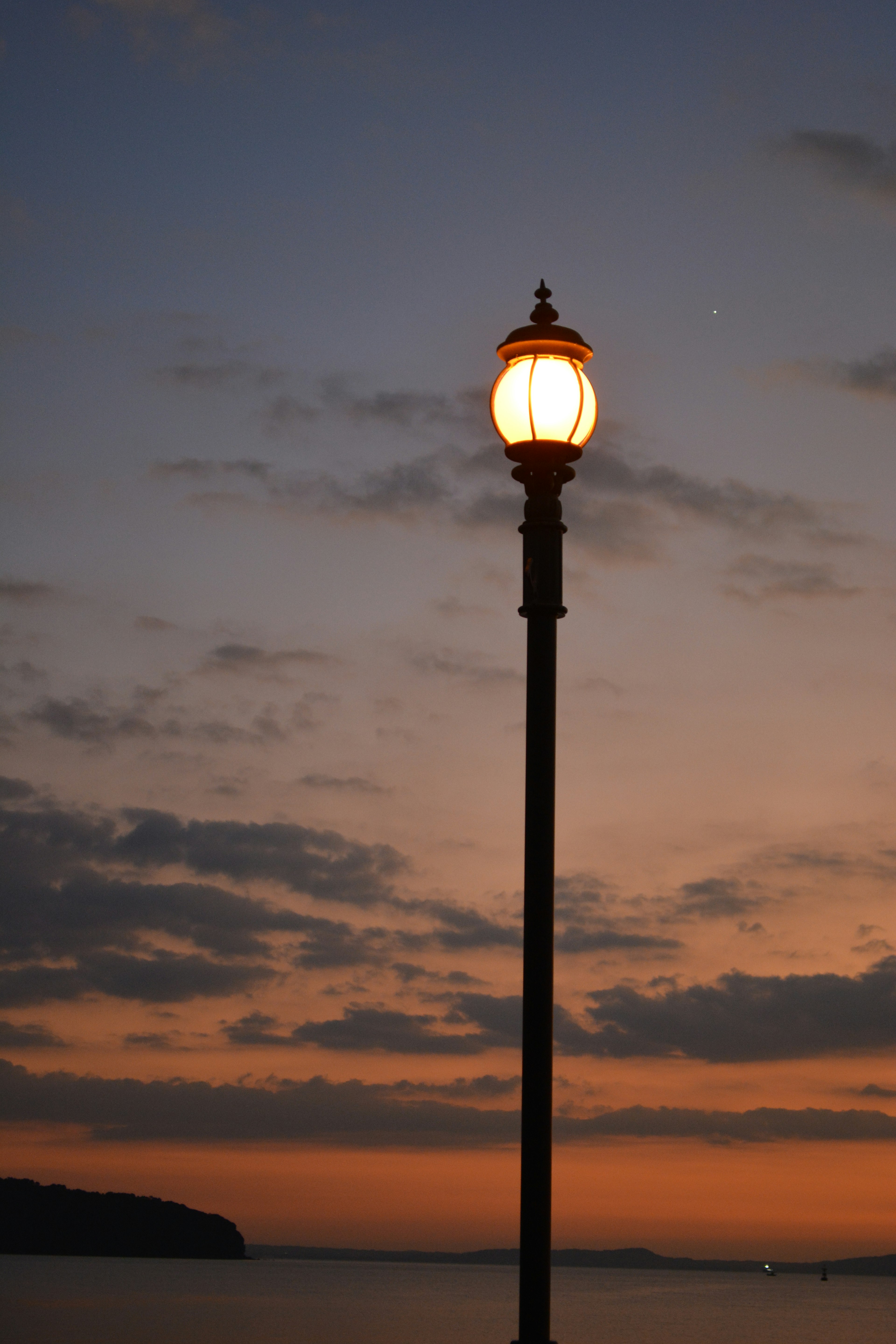 Farola iluminada contra un cielo al atardecer