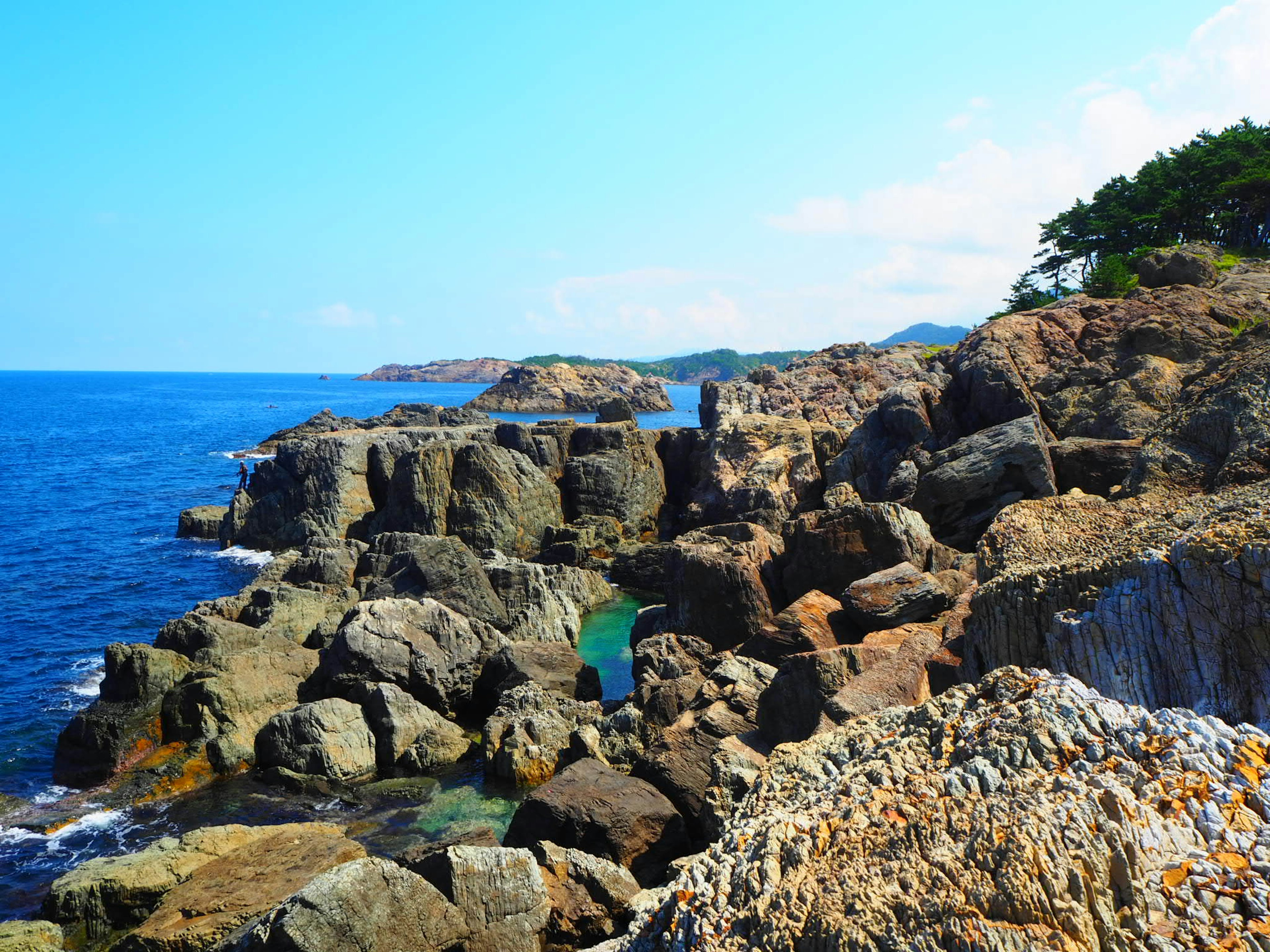 Costa rocciosa con mare blu chiaro