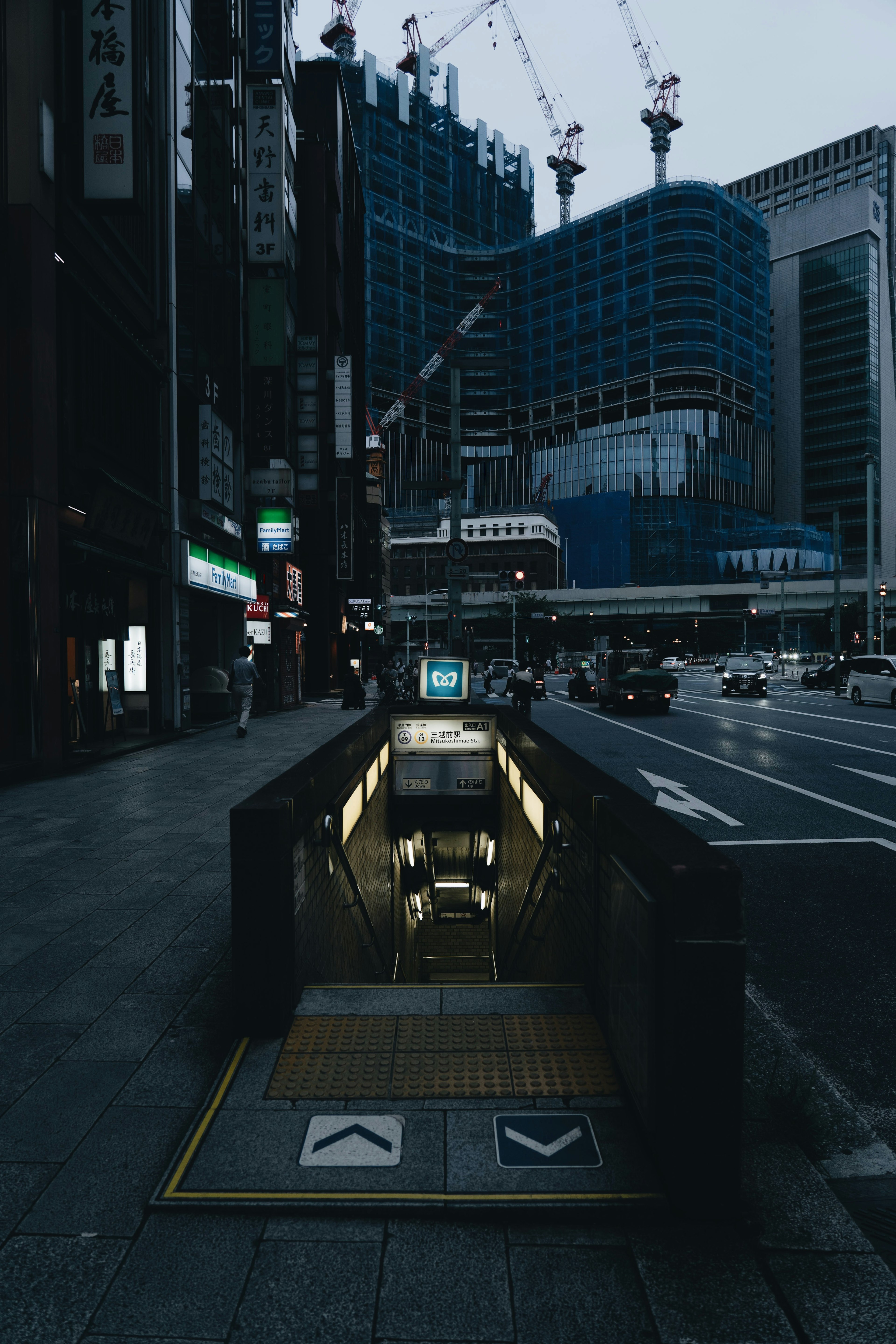 Subway entrance in a dark city street with high-rise buildings in the background