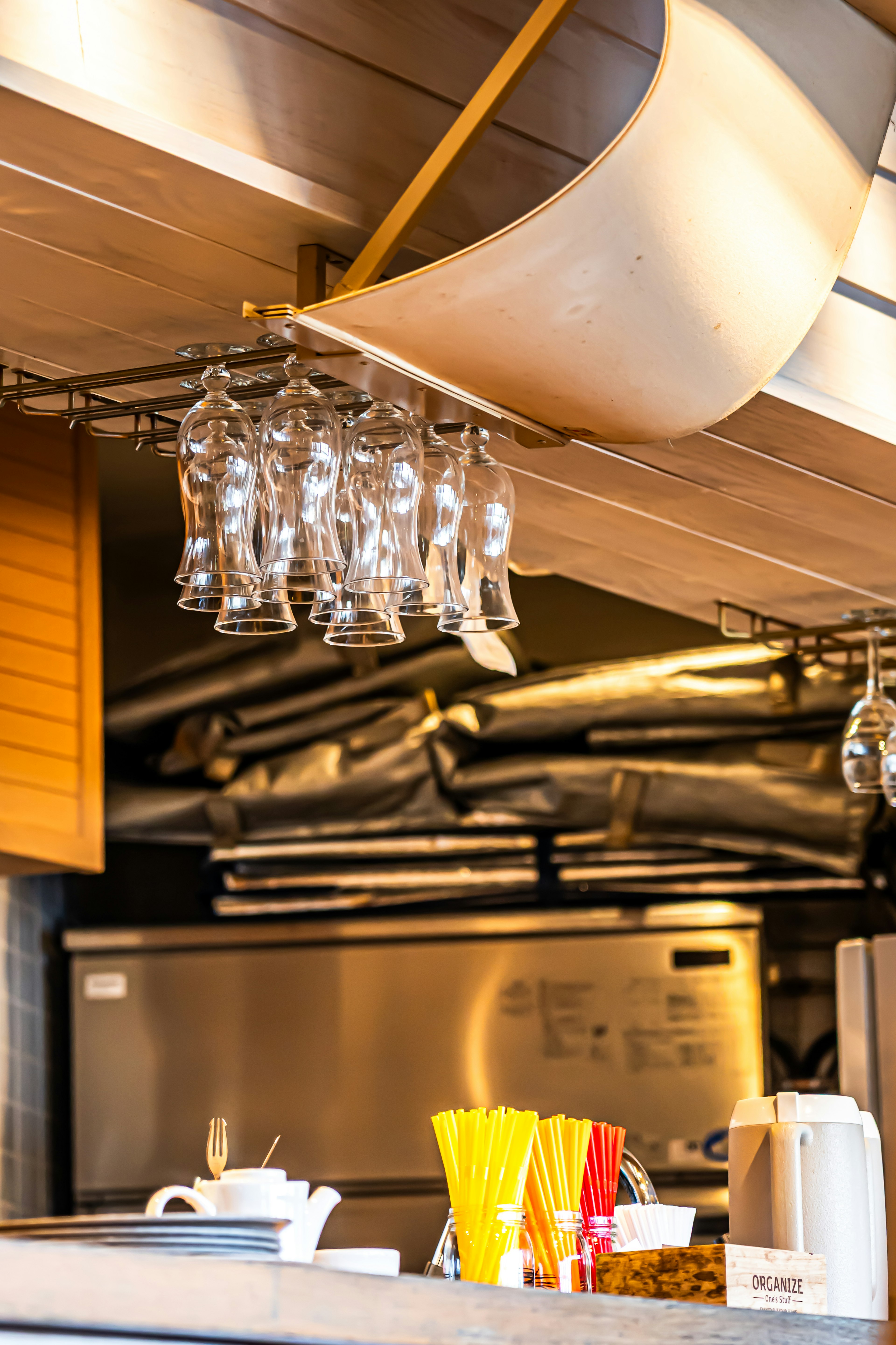 Interior of a cafe featuring hanging glasses and colorful straws