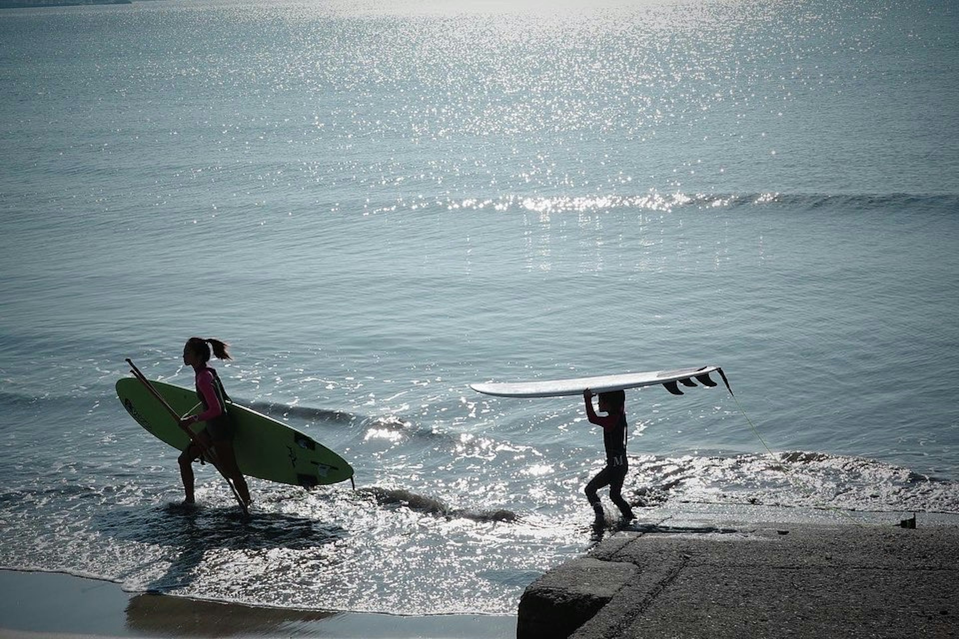 Bambini che camminano sulla spiaggia con tavole da surf