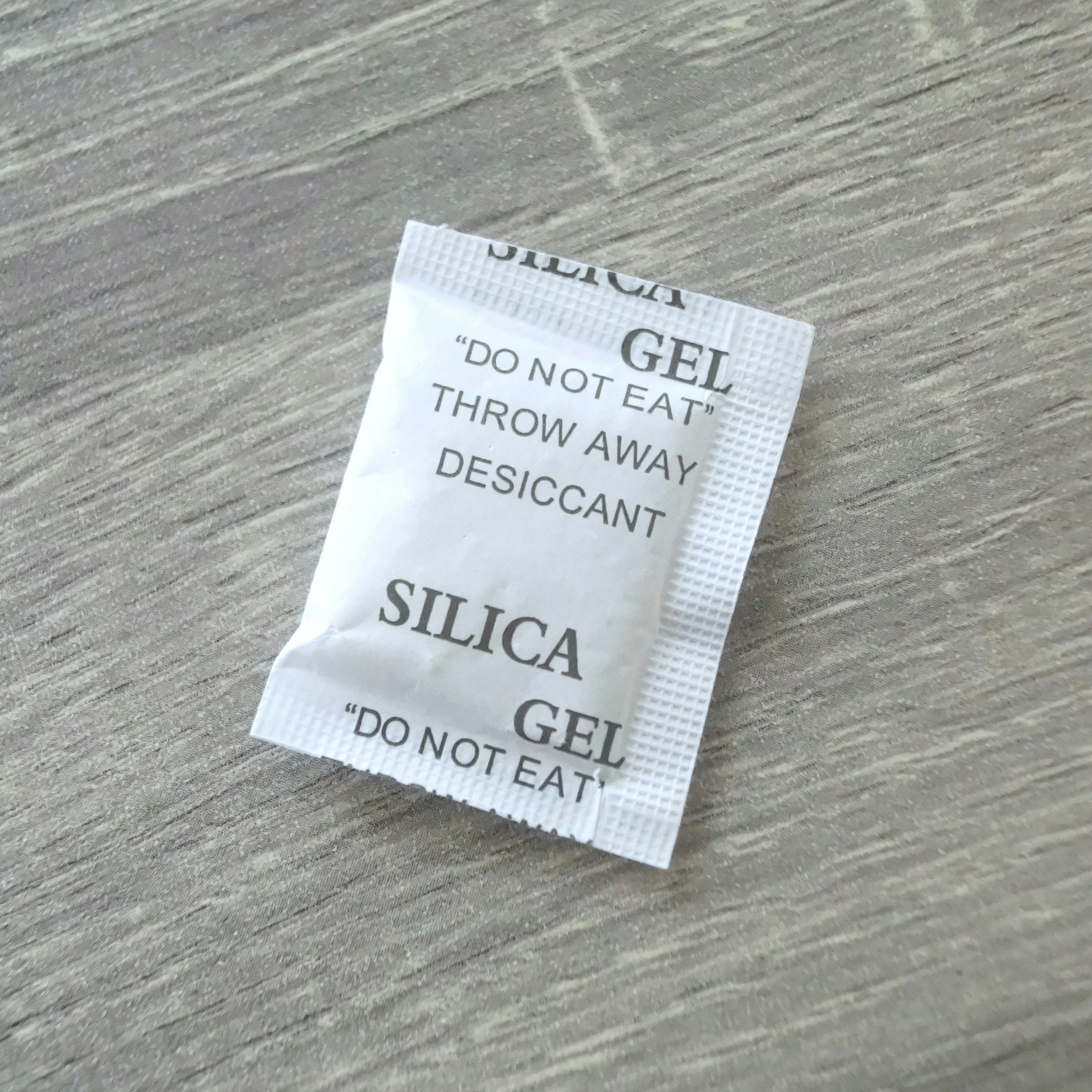 Silica gel packet placed on a wooden table surface