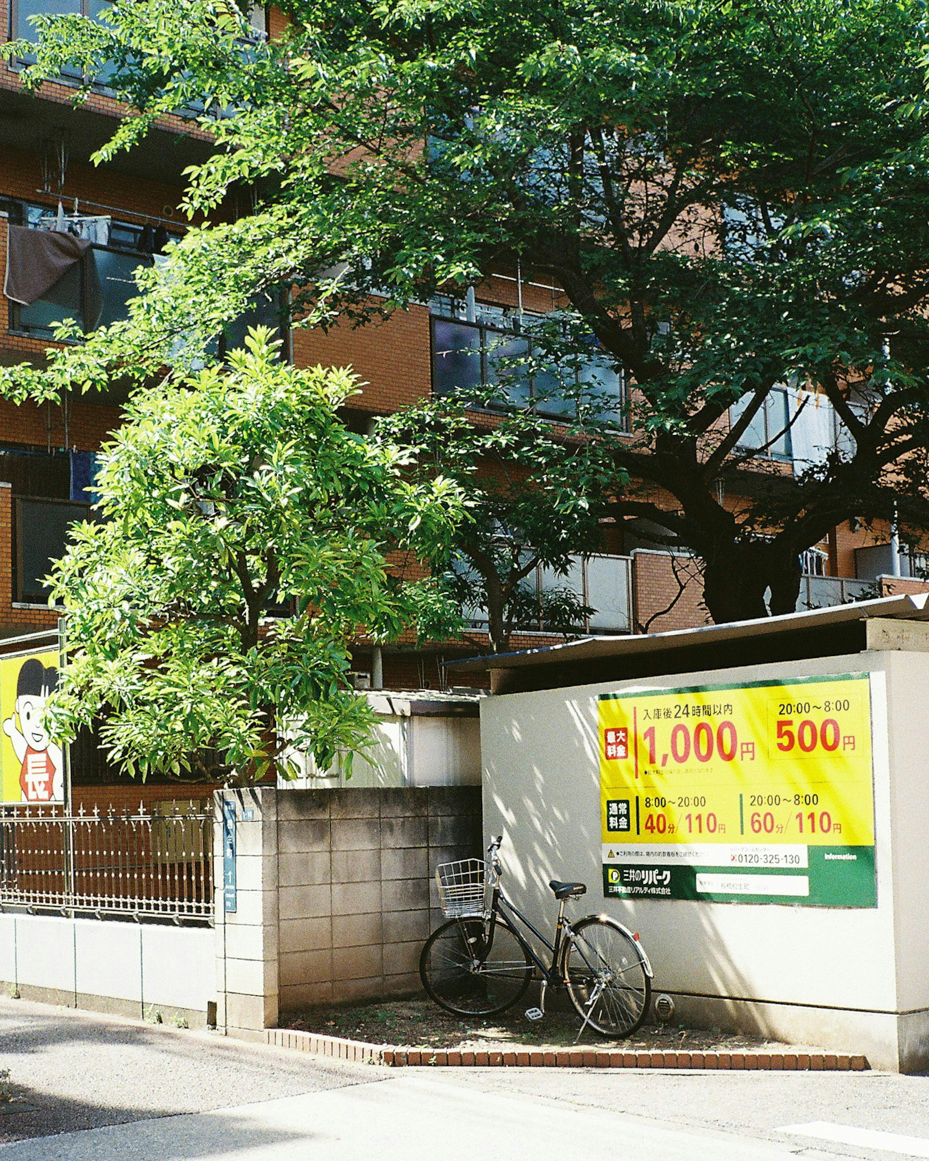 Apartment exterior with a bicycle and greenery featuring a prominent advertisement