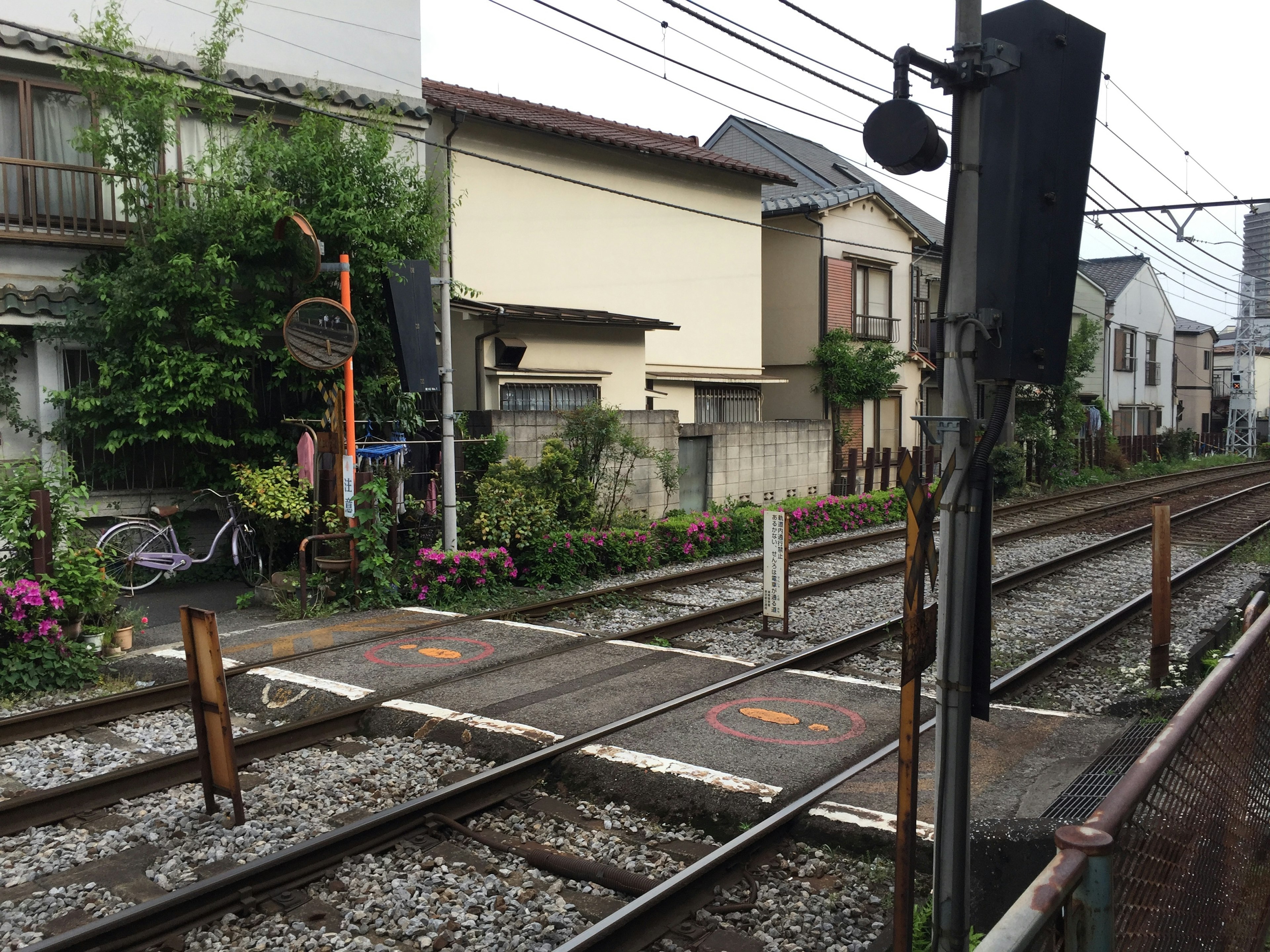 駅近くの線路と住宅街の風景　緑豊かな植物と自転車が見える