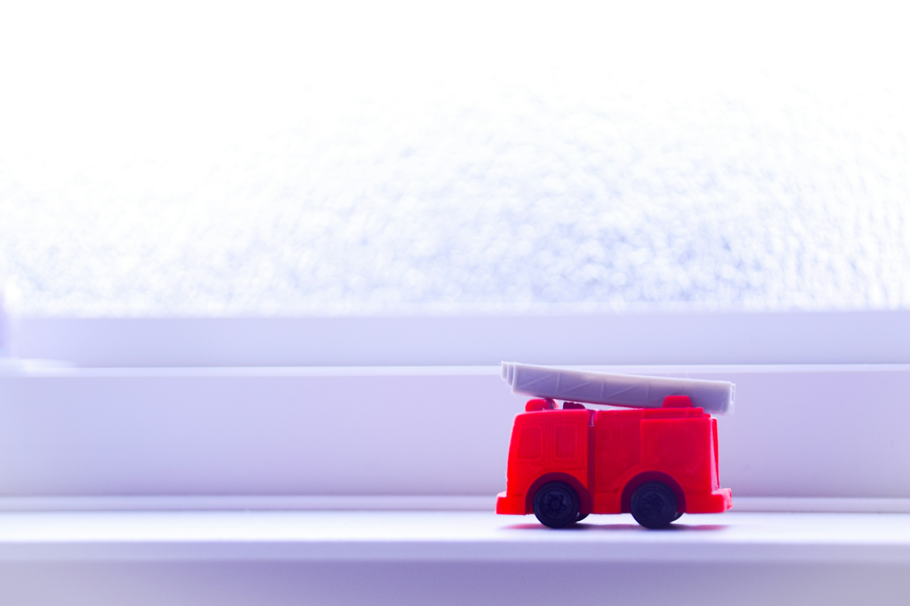 A miniature red fire truck placed on a windowsill