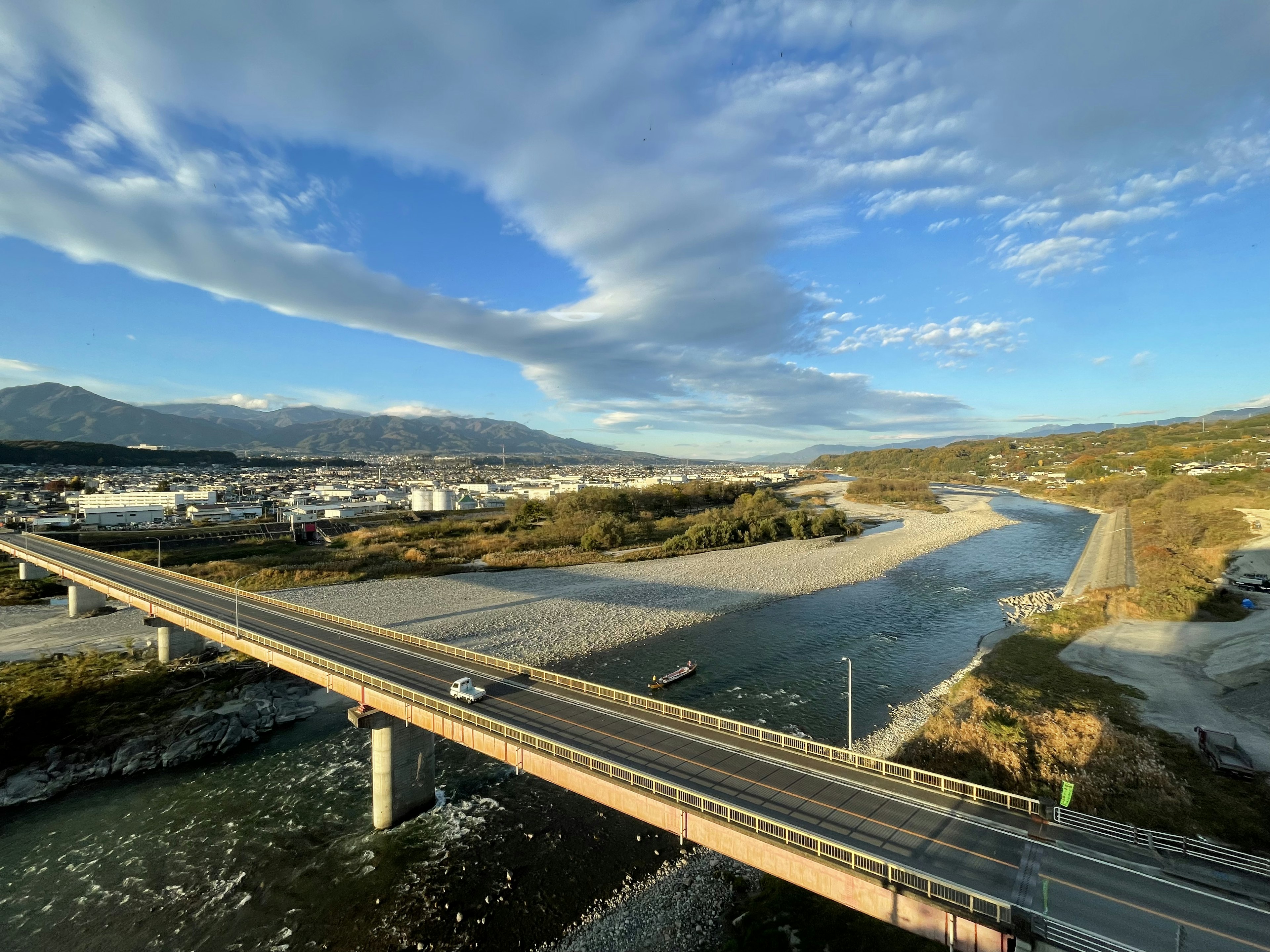 Puente sobre un río con cielo despejado y nubes dispersas