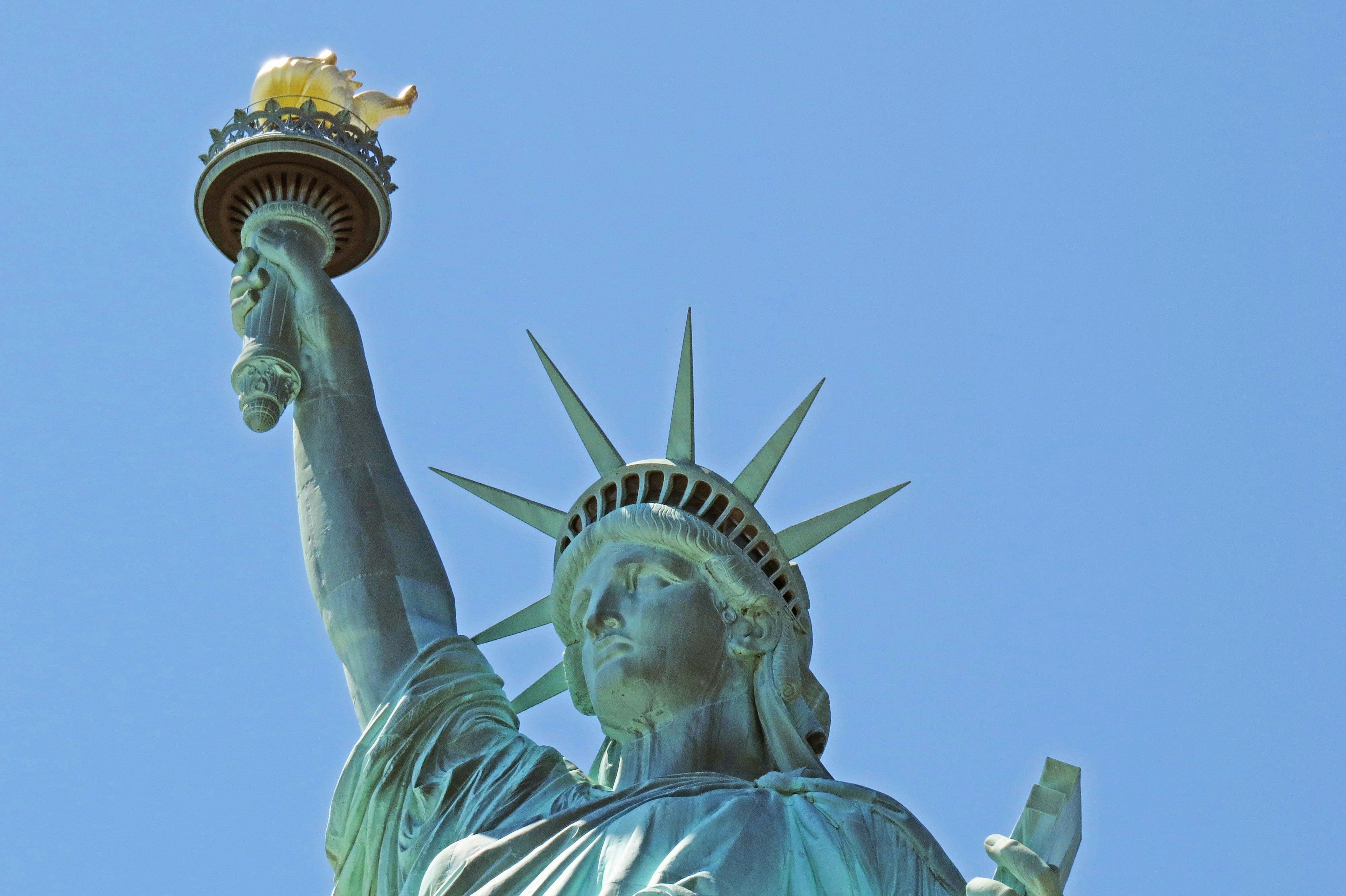 Freiheitsstatue hält eine Fackel vor einem klaren blauen Himmel