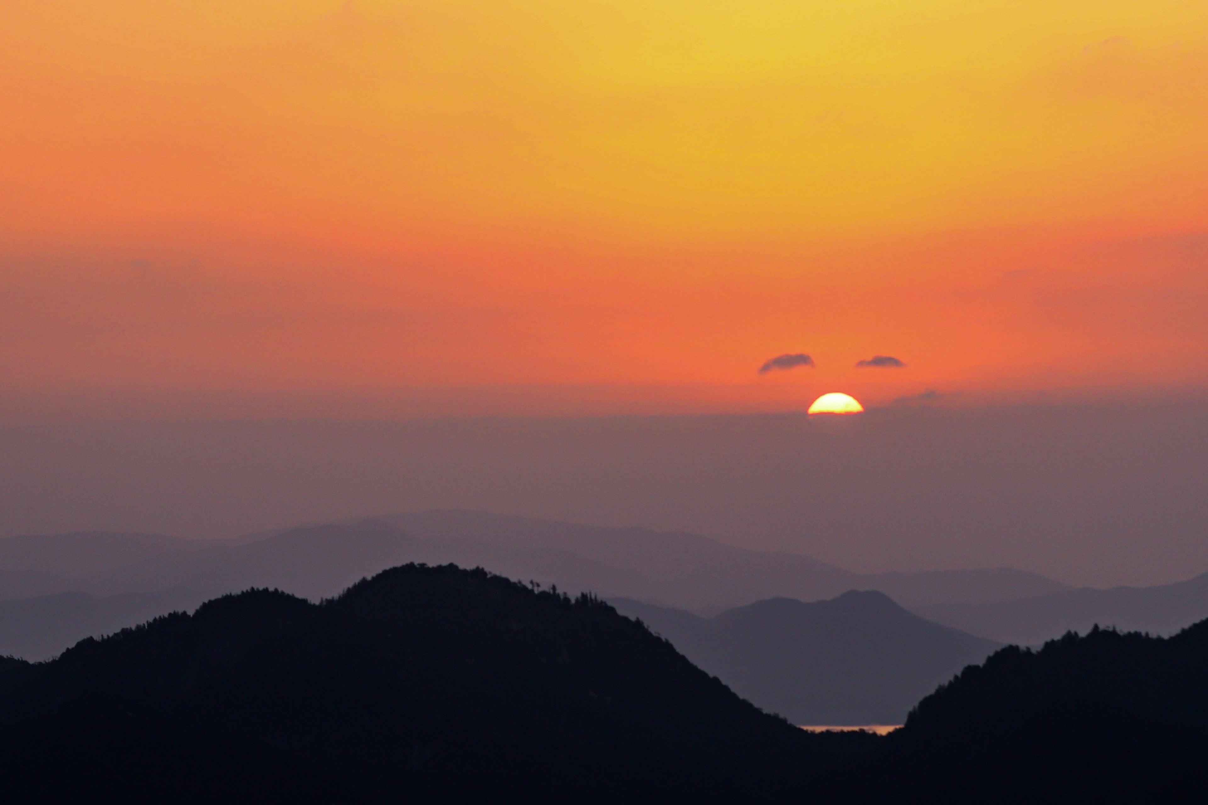 Hermoso paisaje del atardecer detrás de montañas con cielo naranja y siluetas de montañas