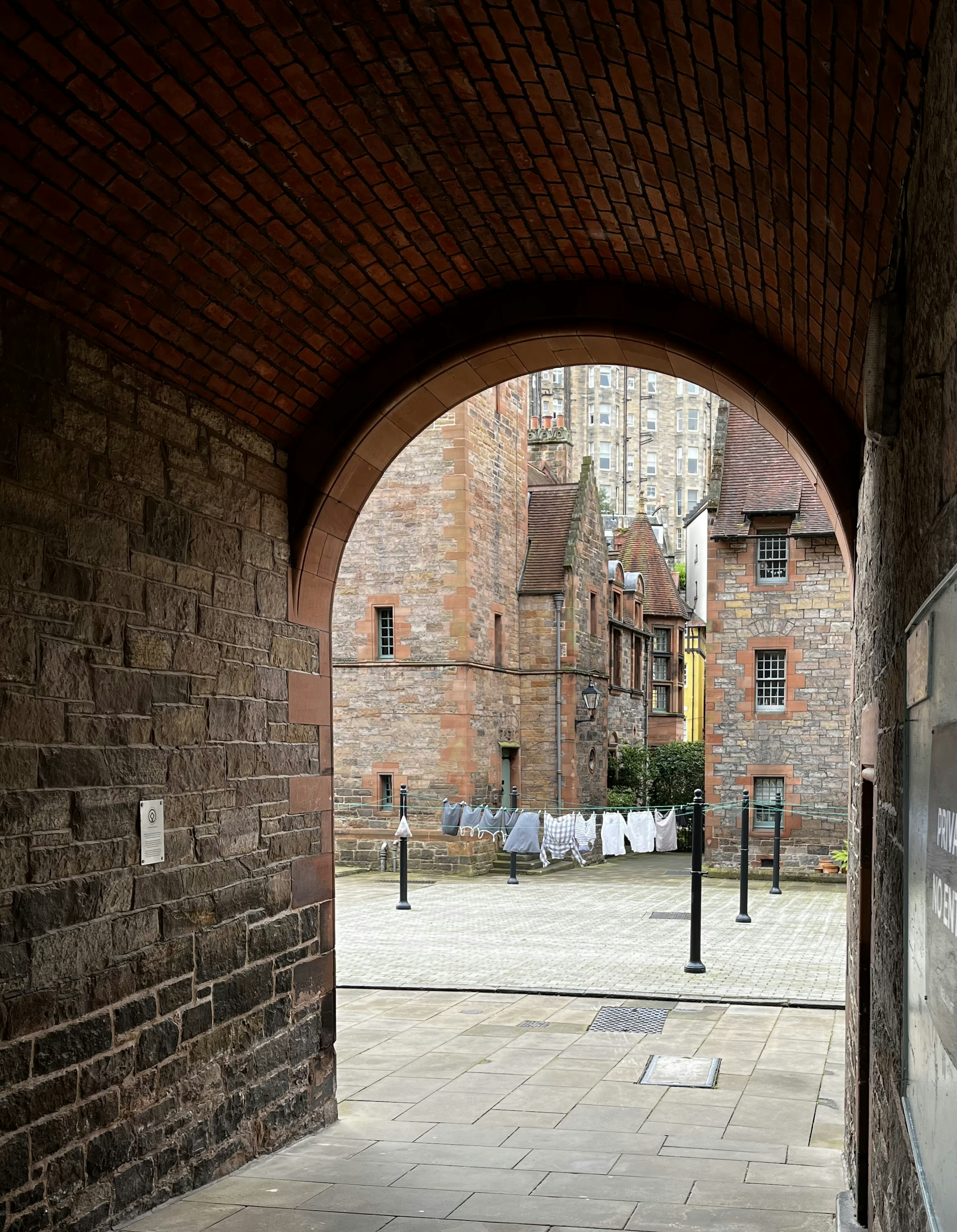 Archway view of old brick buildings with laundry hanging