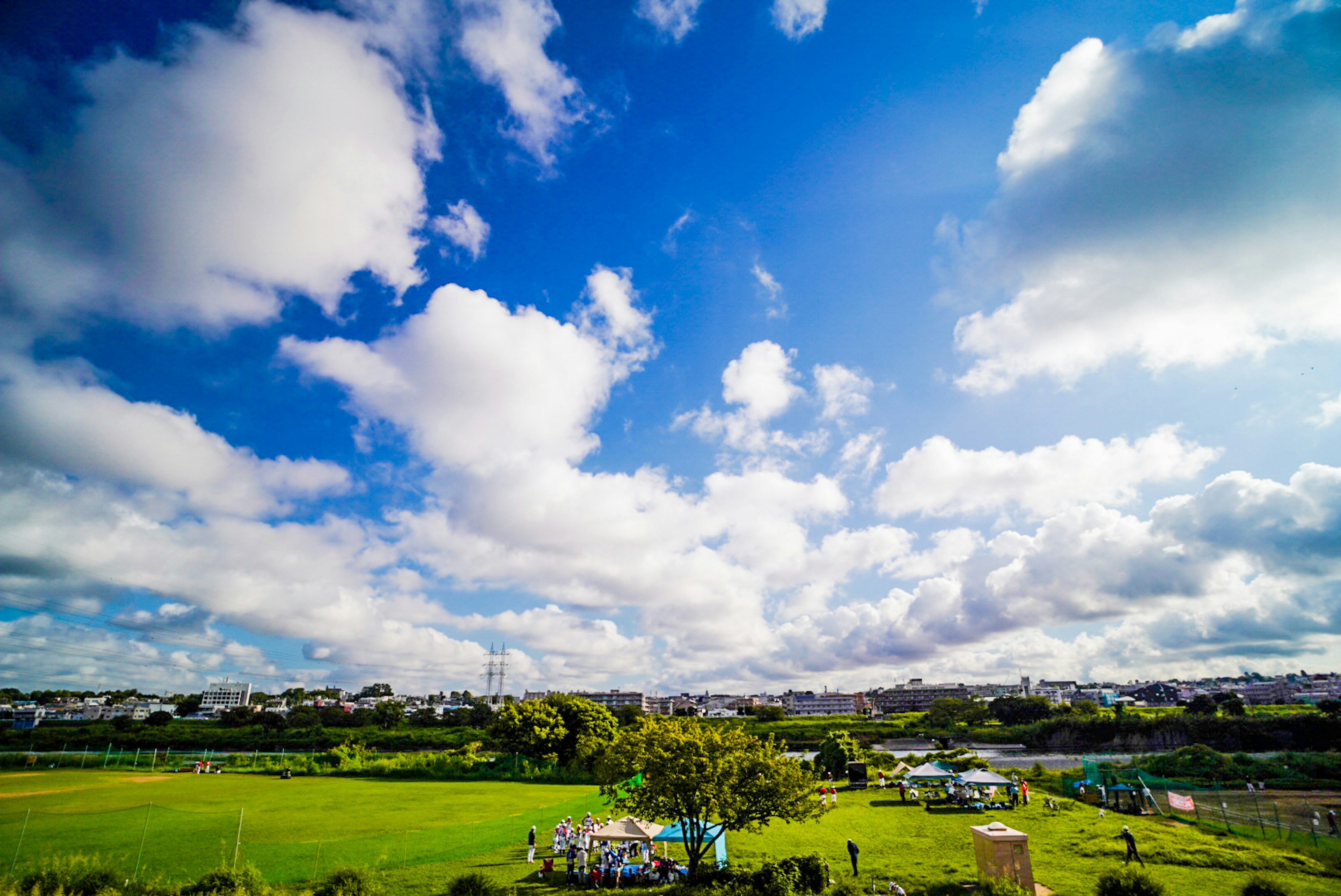 青空と白い雲が広がる風景 緑豊かな草原と小屋が見える