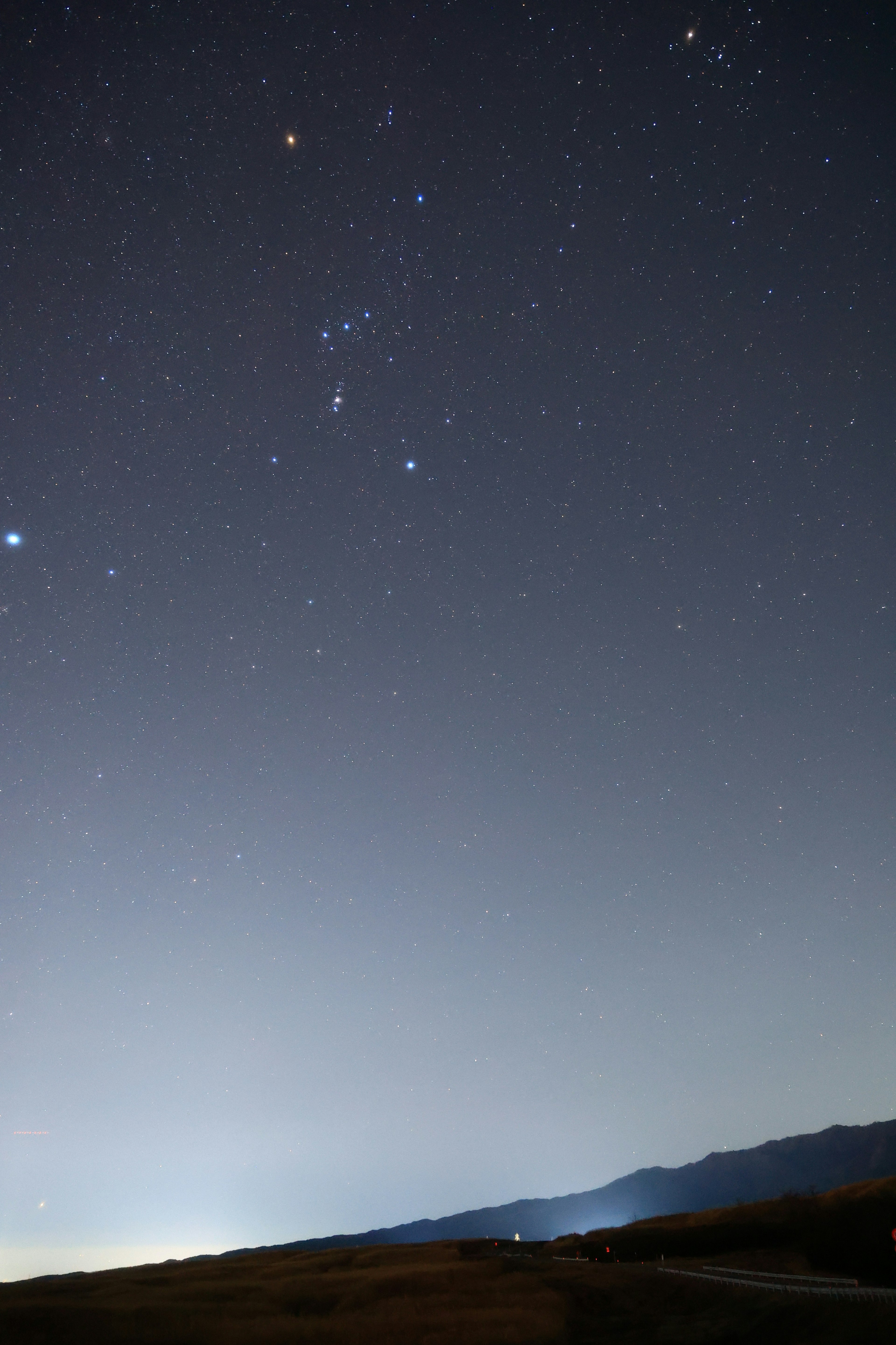 A serene landscape under the starry sky with mountains and bright stars visible