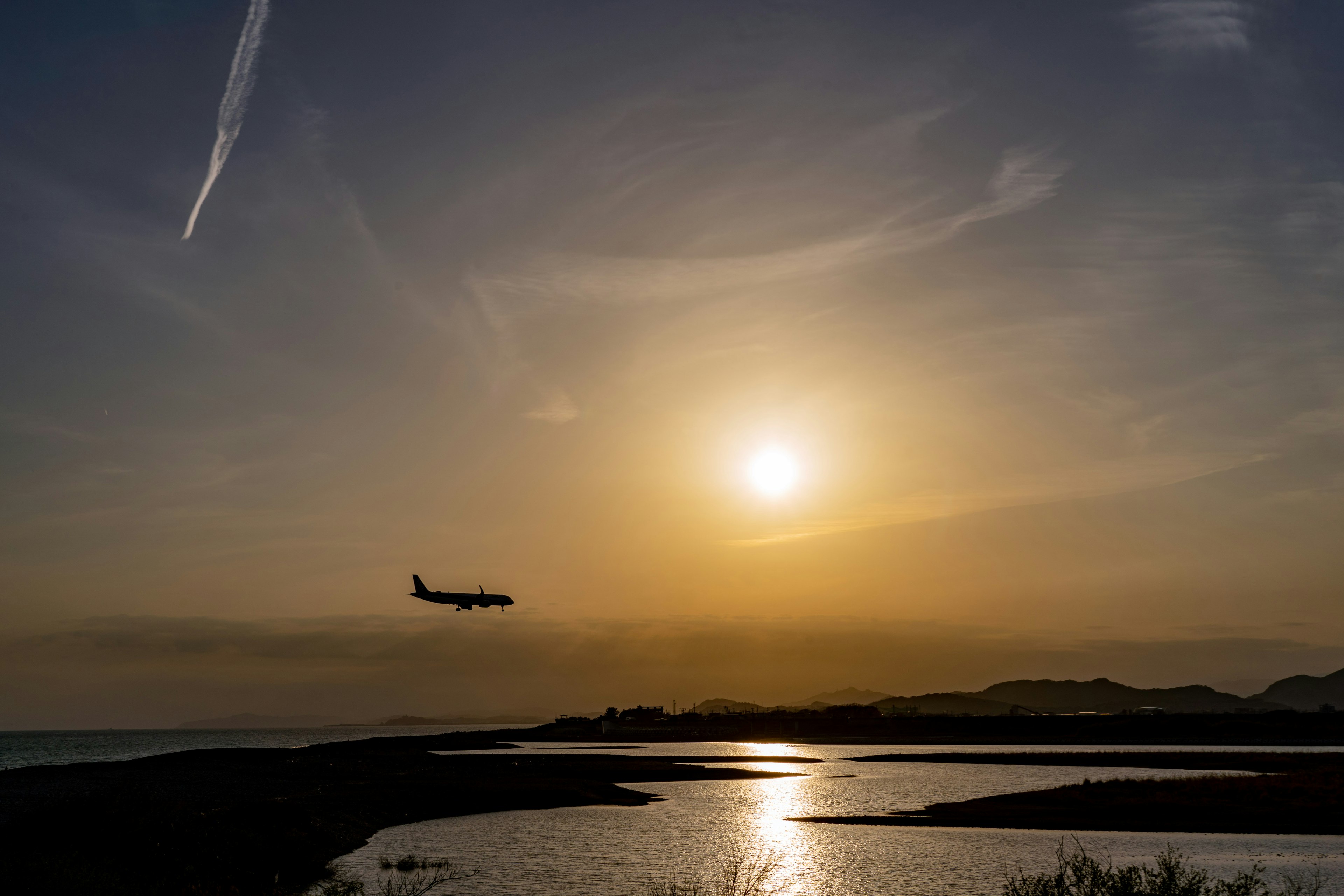 夕日を背景に飛行機が飛んでいるシルエットの風景