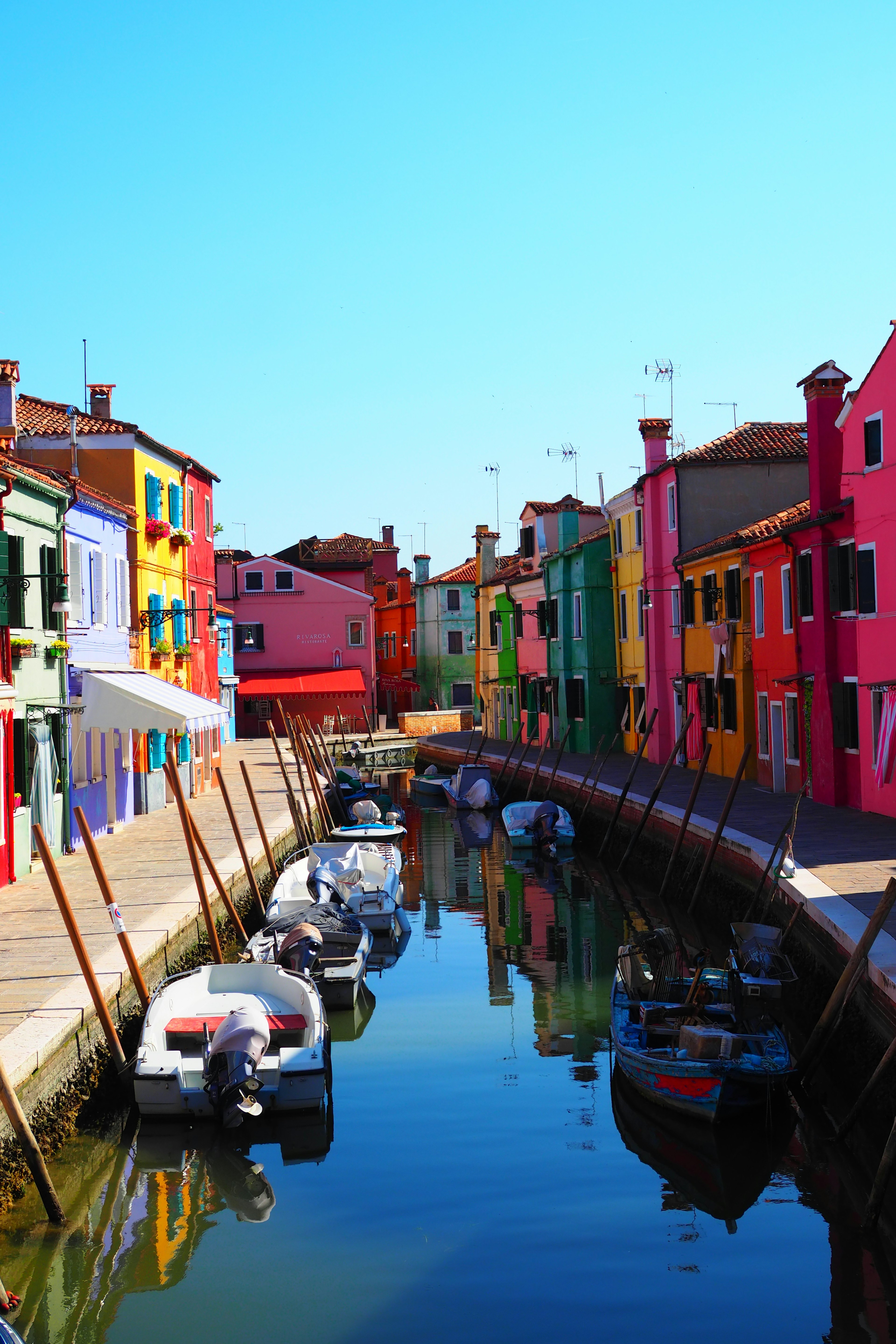 Colorful buildings lining a canal scene in Burano with boats reflecting in the water