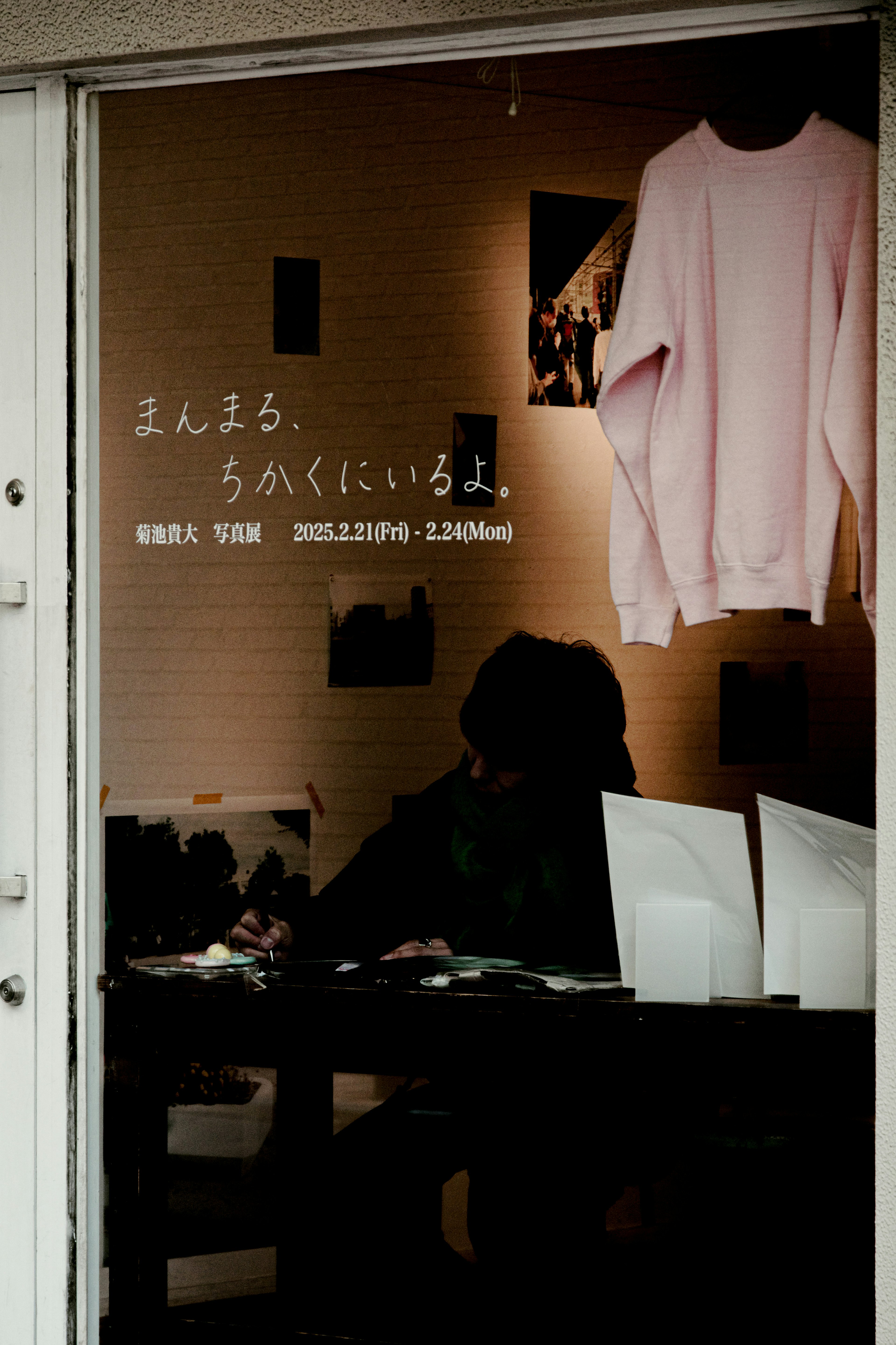 Silhouette of a person sitting behind a window with a pink sweater displayed