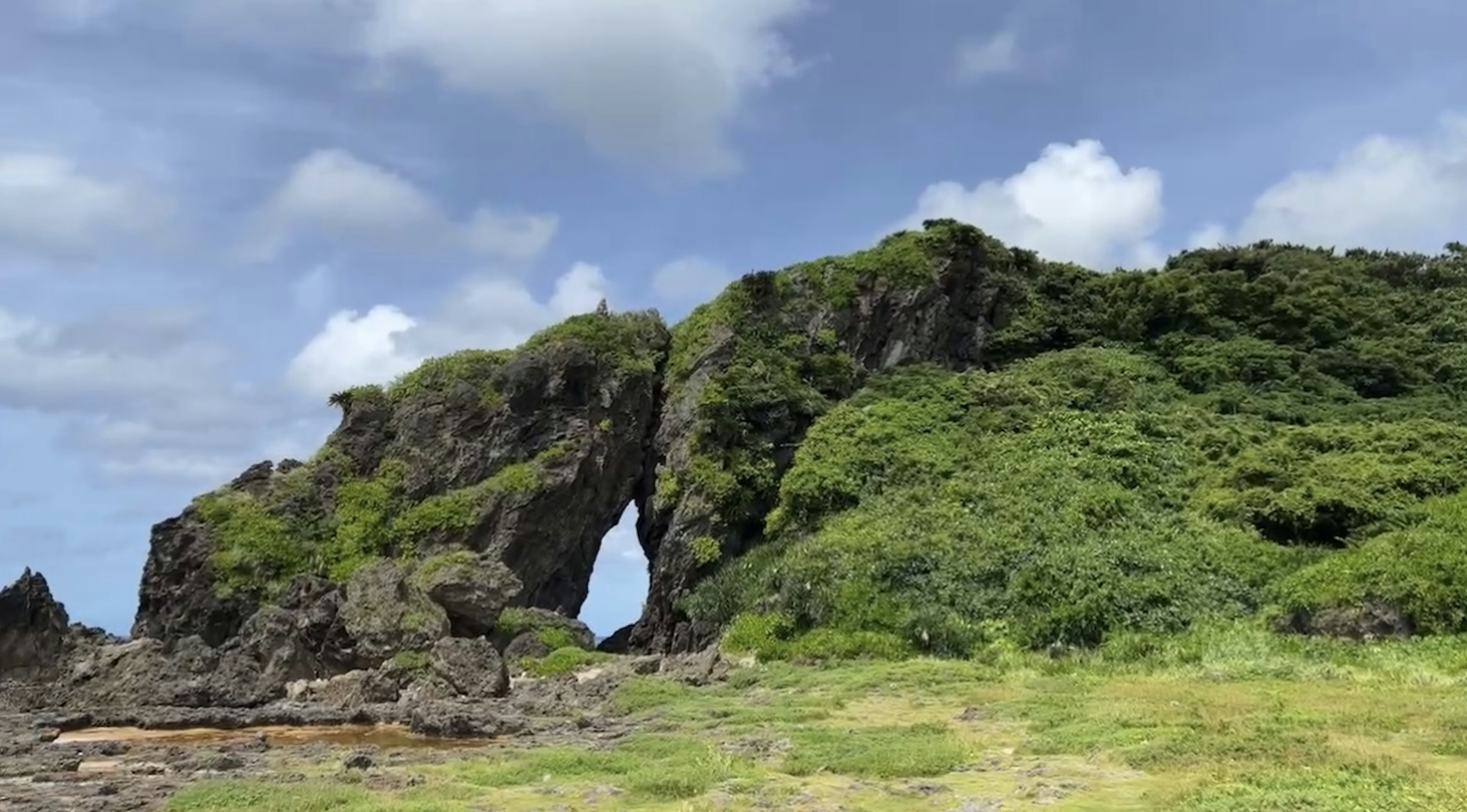 Arc rocheux couvert de verdure sous un ciel bleu