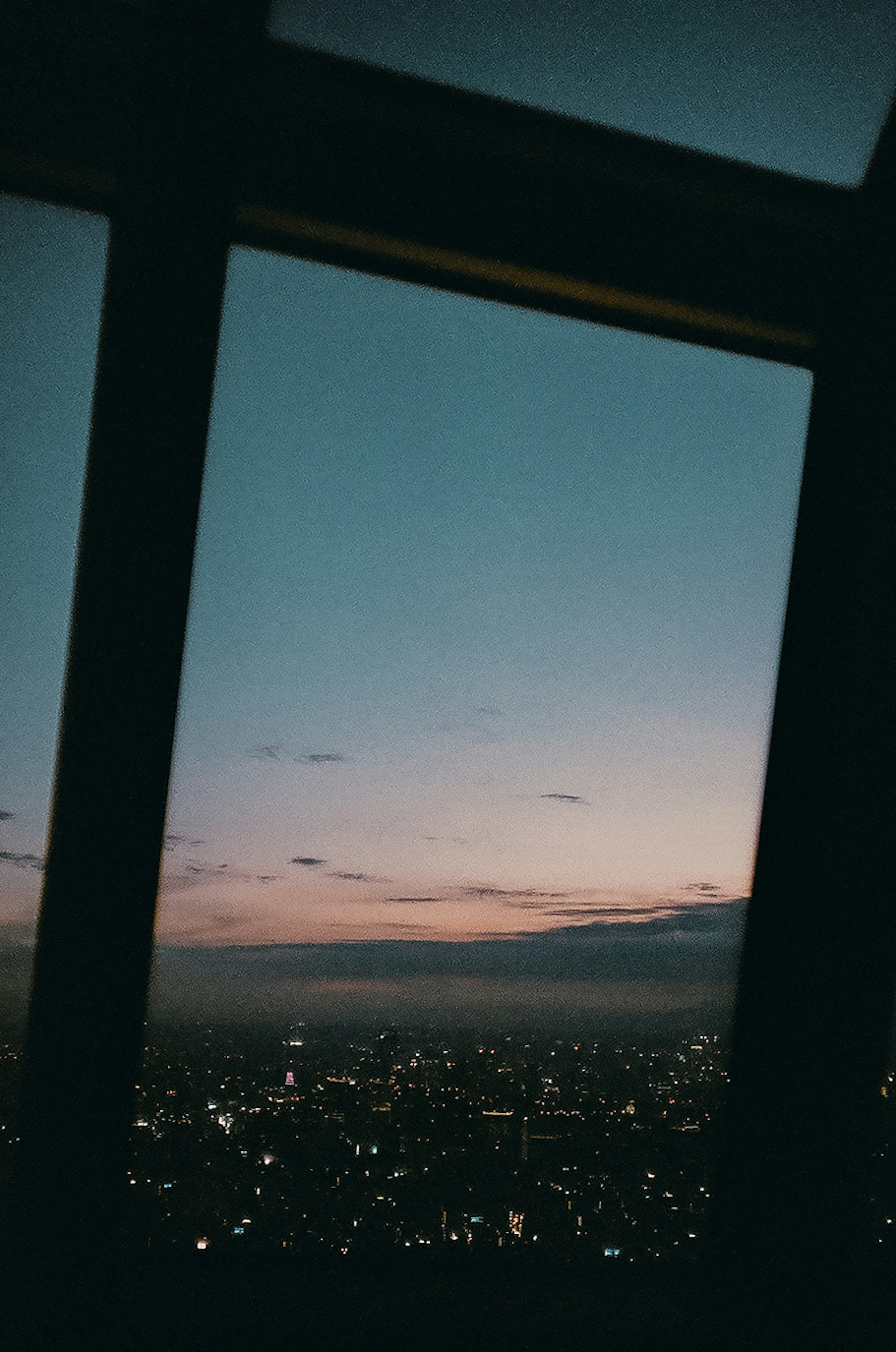 Blick auf eine Stadt bei Dämmerung durch ein Fenster mit funkelnden Lichtern