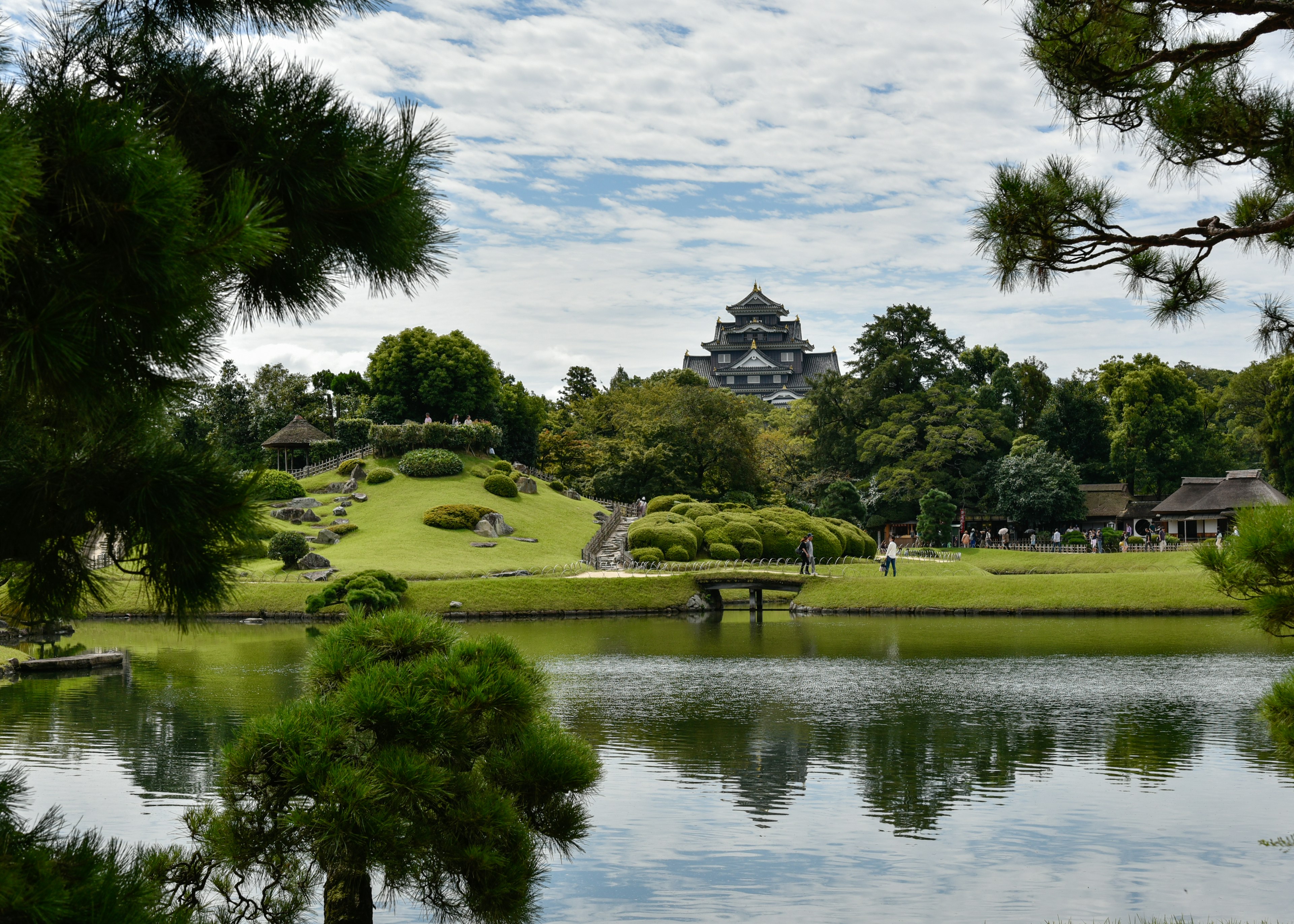 Vue pittoresque d'un étang tranquille reflétant un beau jardin avec un château japonais en arrière-plan