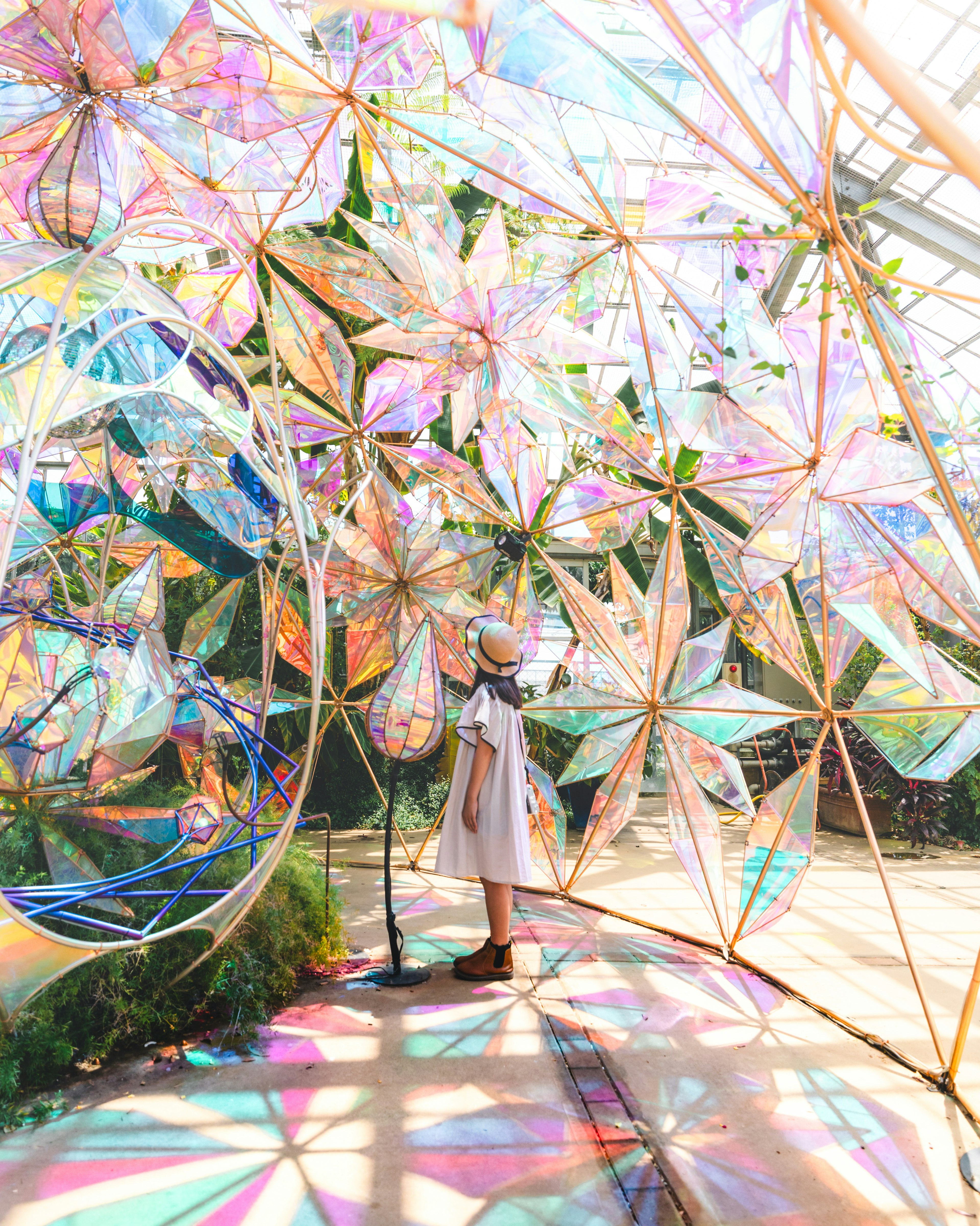 A woman standing in a space filled with colorful transparent flower-shaped decorations