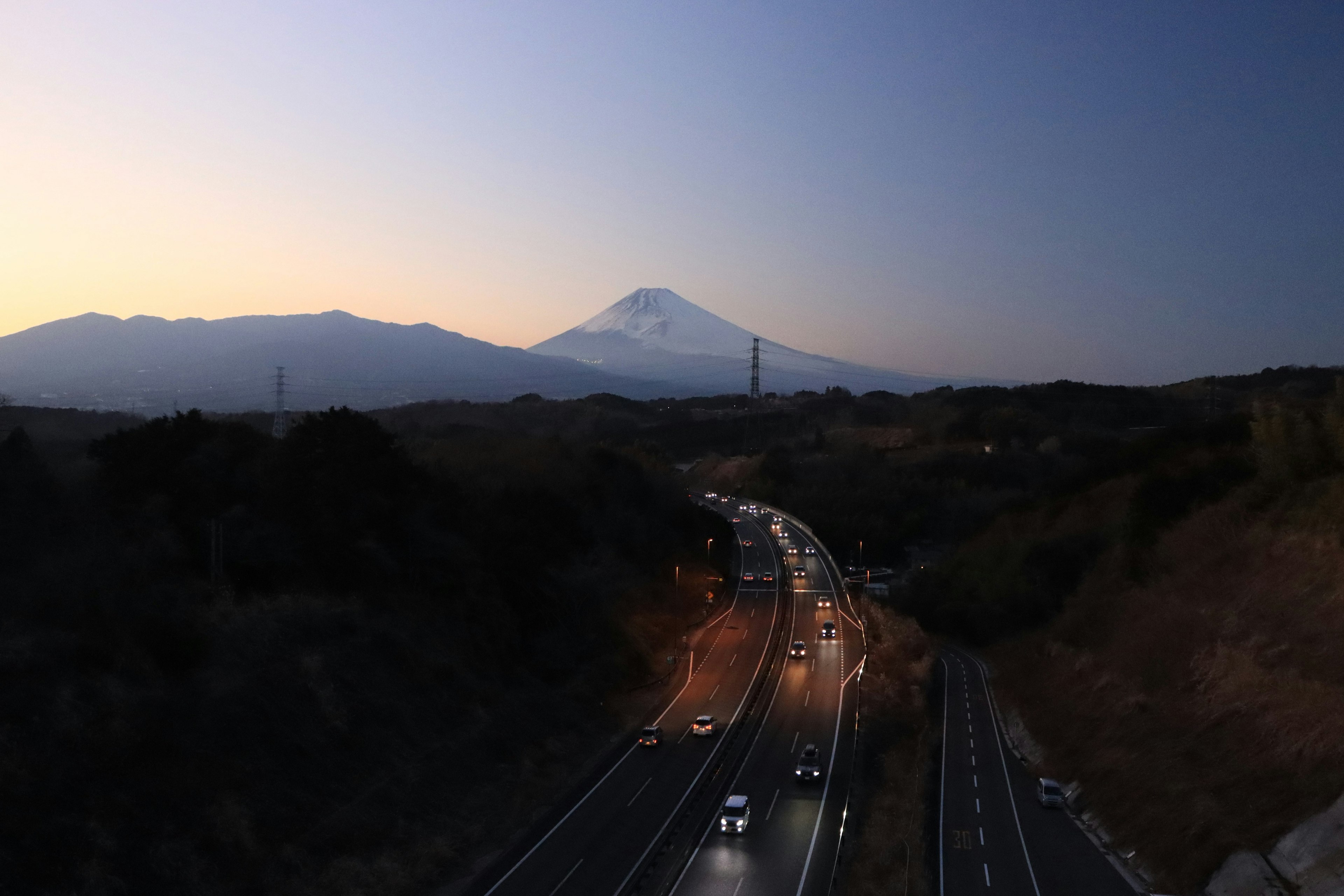 Vue du soir du mont Fuji avec une route sinueuse et des phares de voiture