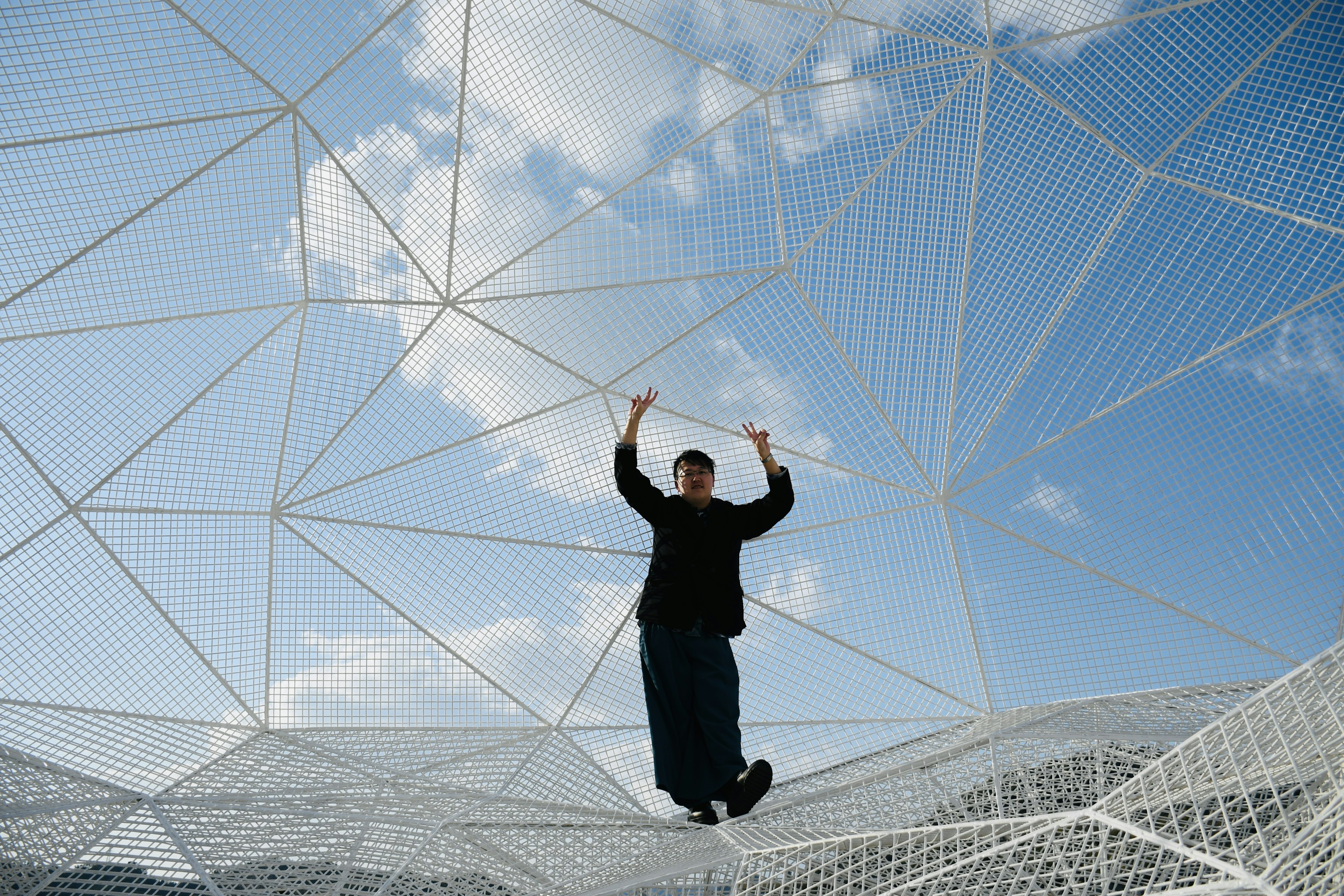 A man standing inside a net structure under a blue sky