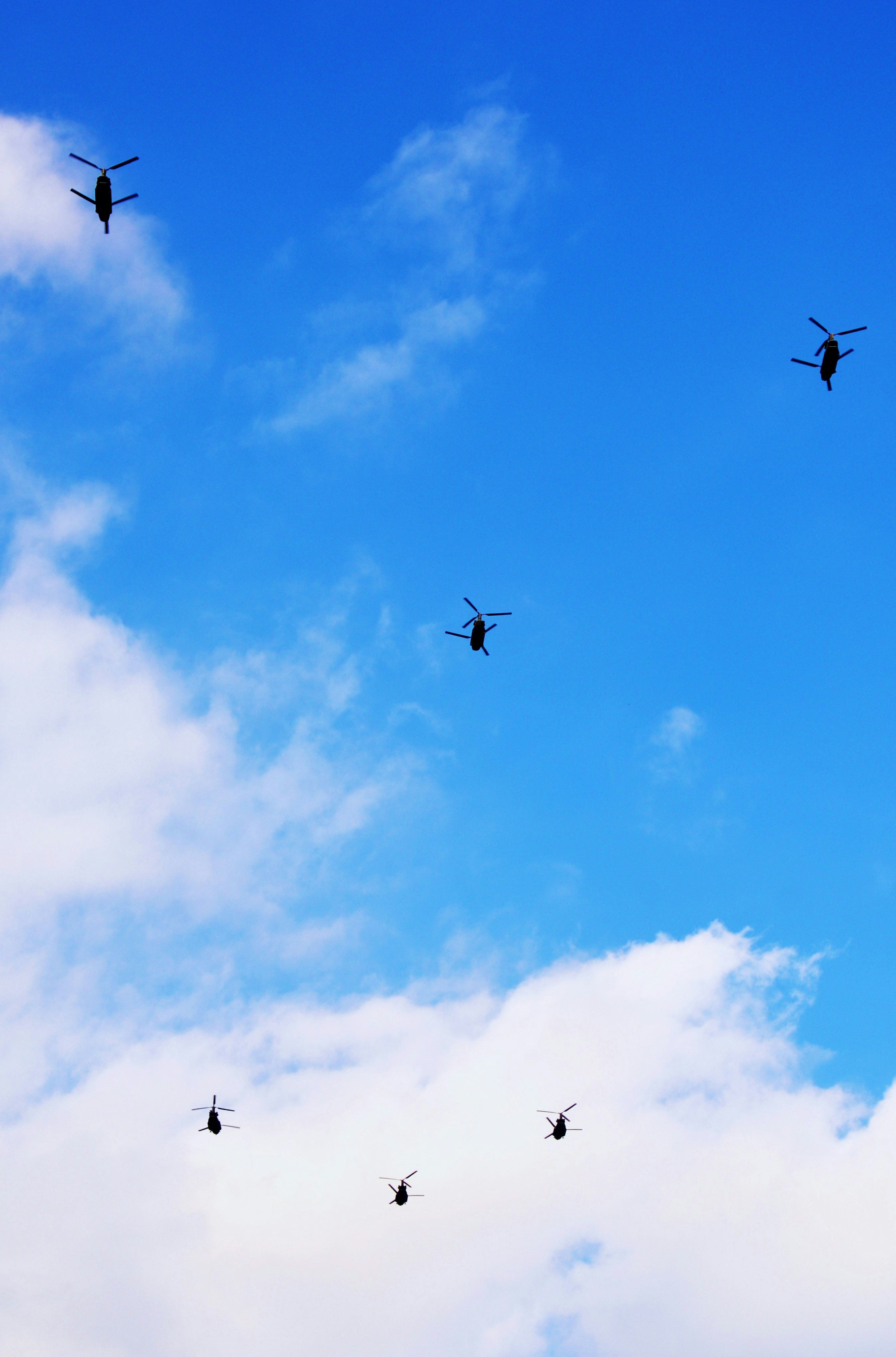 Multiple helicopters flying in a clear blue sky